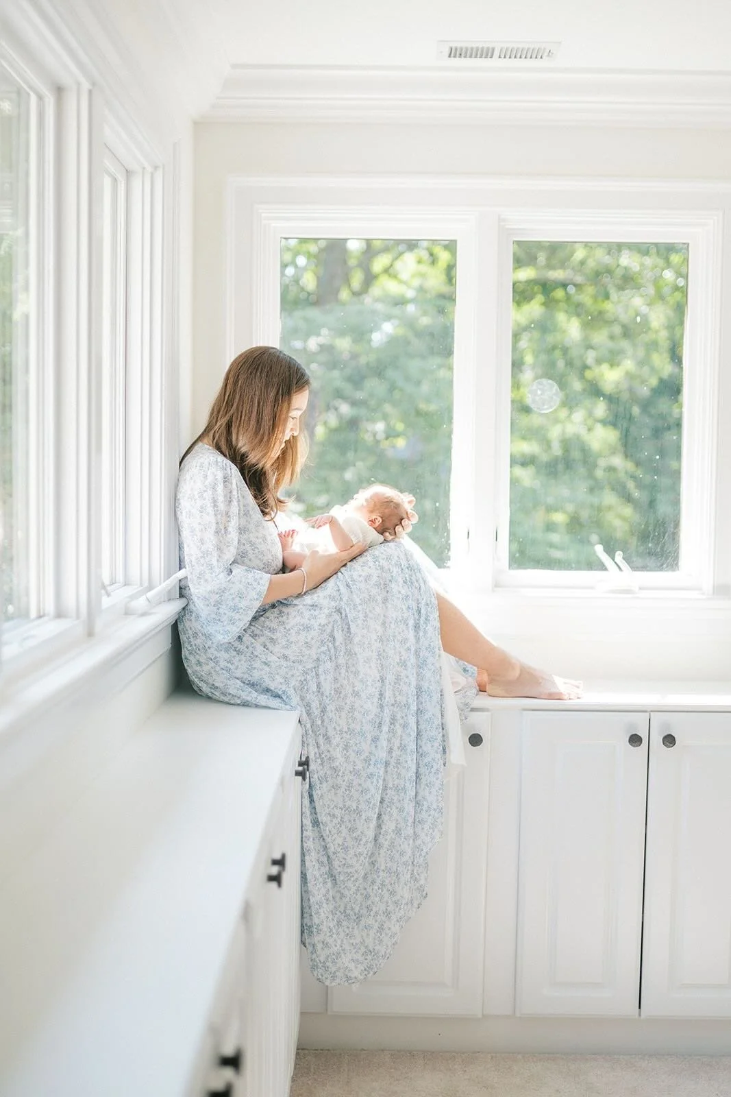 Mother sitting on the counter holding baby boy in the natural light - Raleigh Newborn Photographer