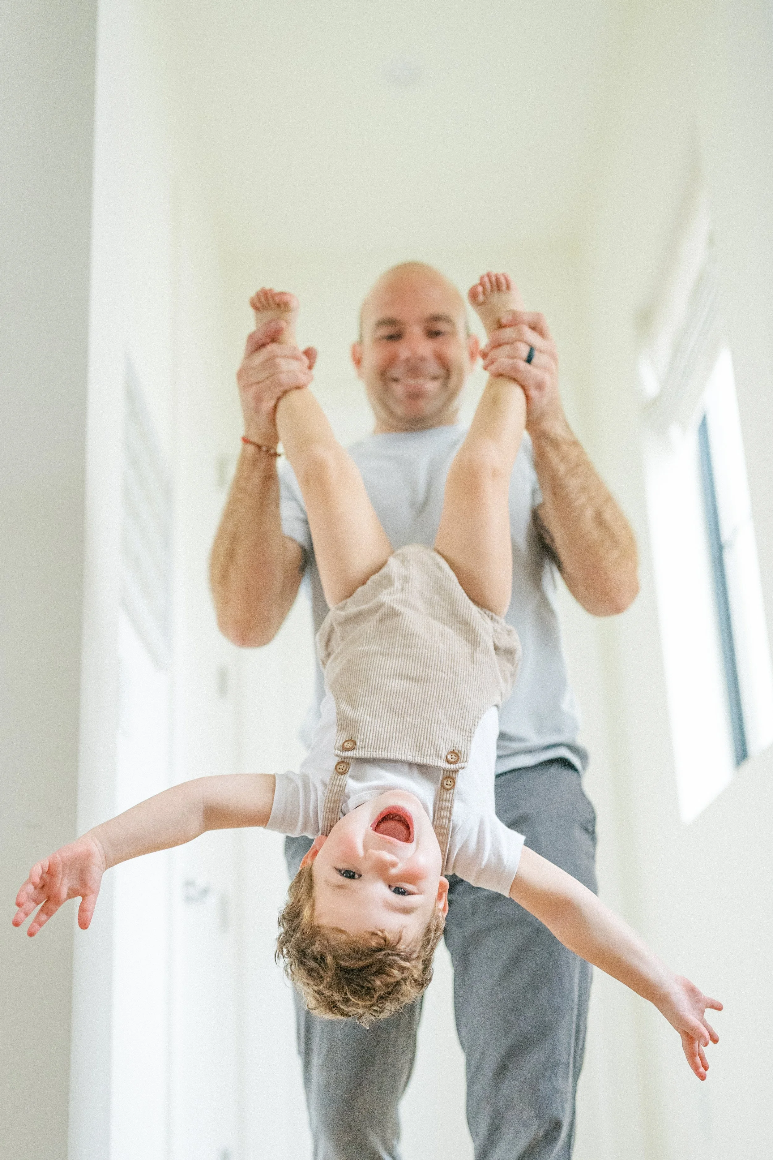 Dad holding his little boy upside down and they're laughing during an in-home family session in Austin, Texas.