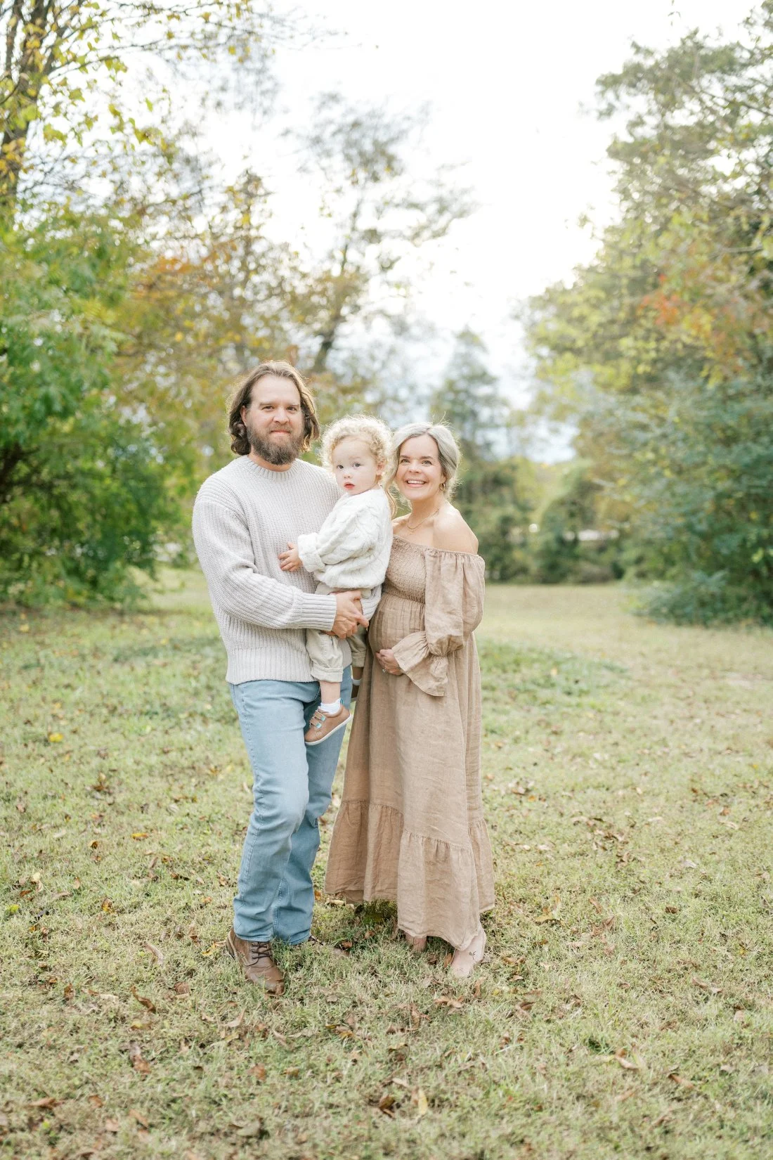 Bad weather photography during an outdoor maternity session with parents holding their toddler on a cloudy Raleigh day.