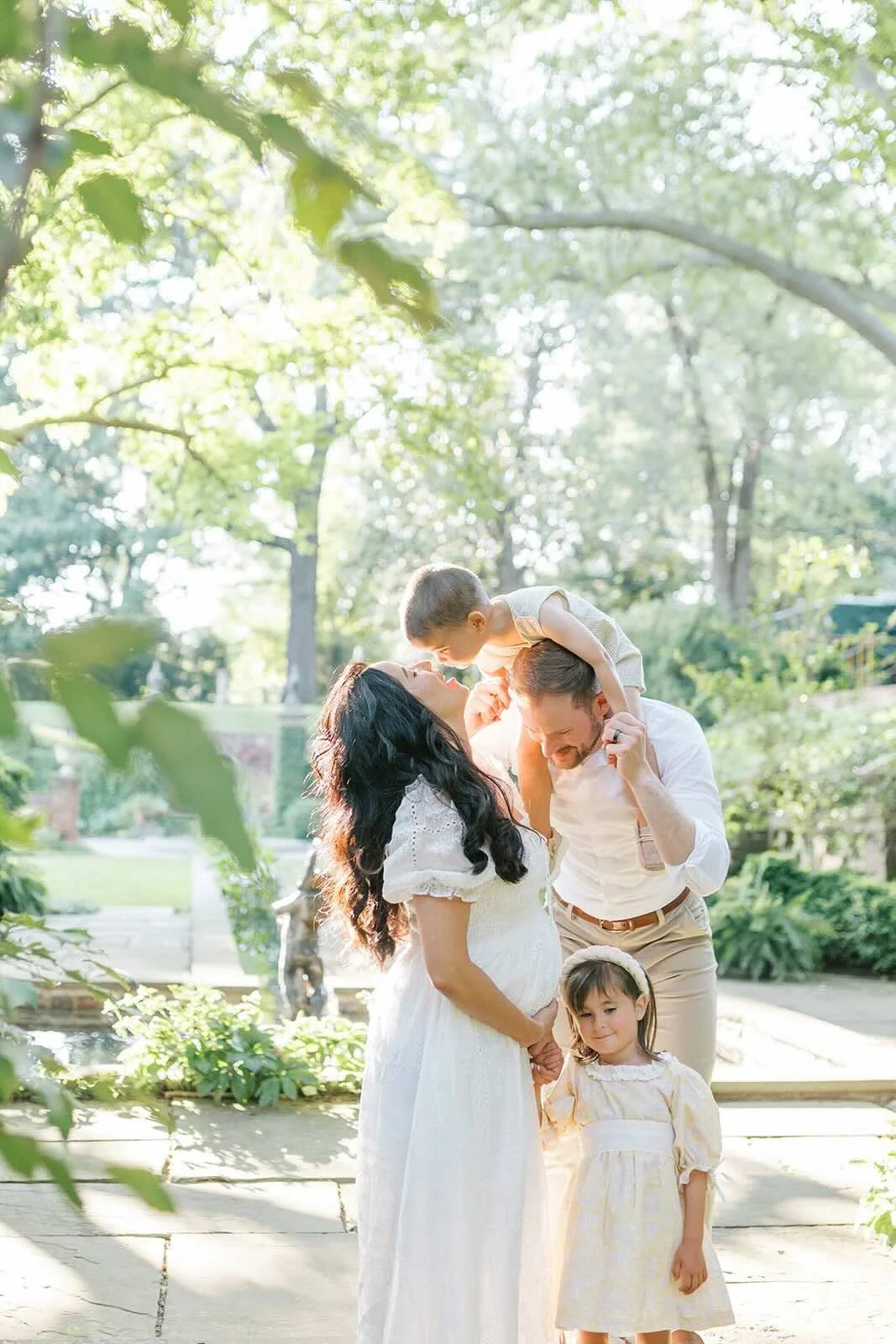 Mom giving son kisses on Dads shoulders while holding her pregnant belly - Raleigh Newborn Photographer