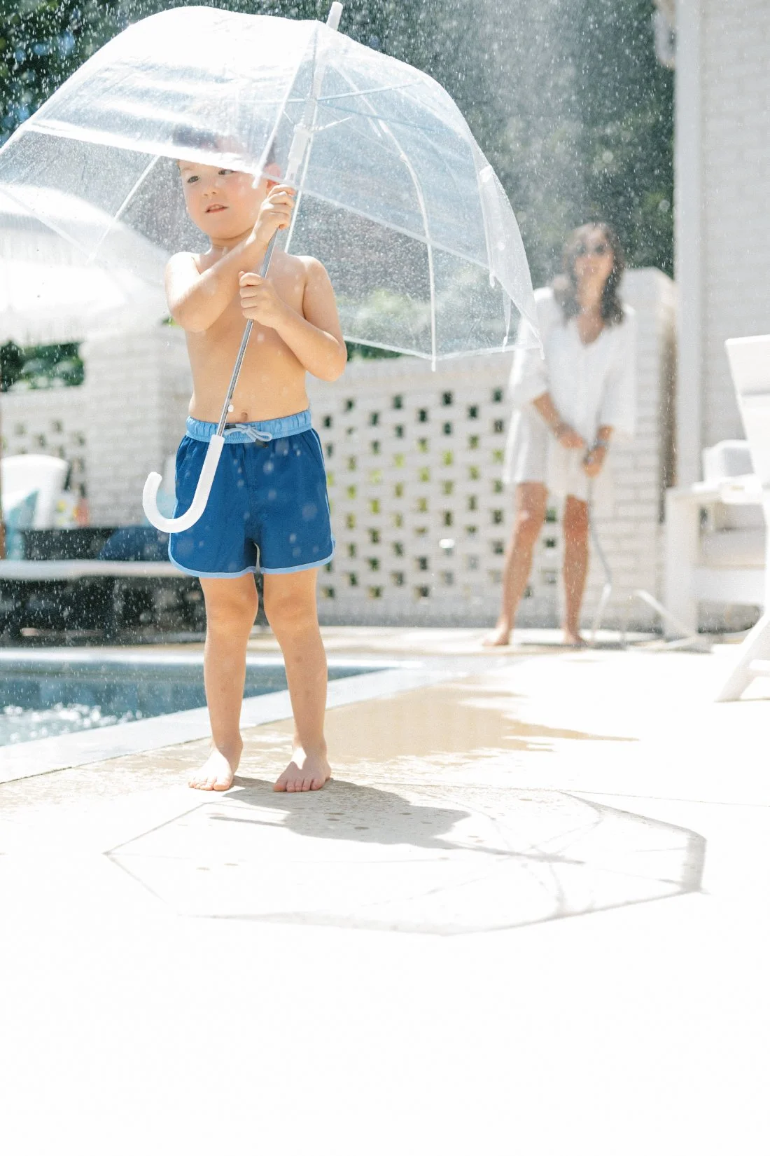 oung boy holding a clear umbrella in the rain during a playful outdoor family photography session.