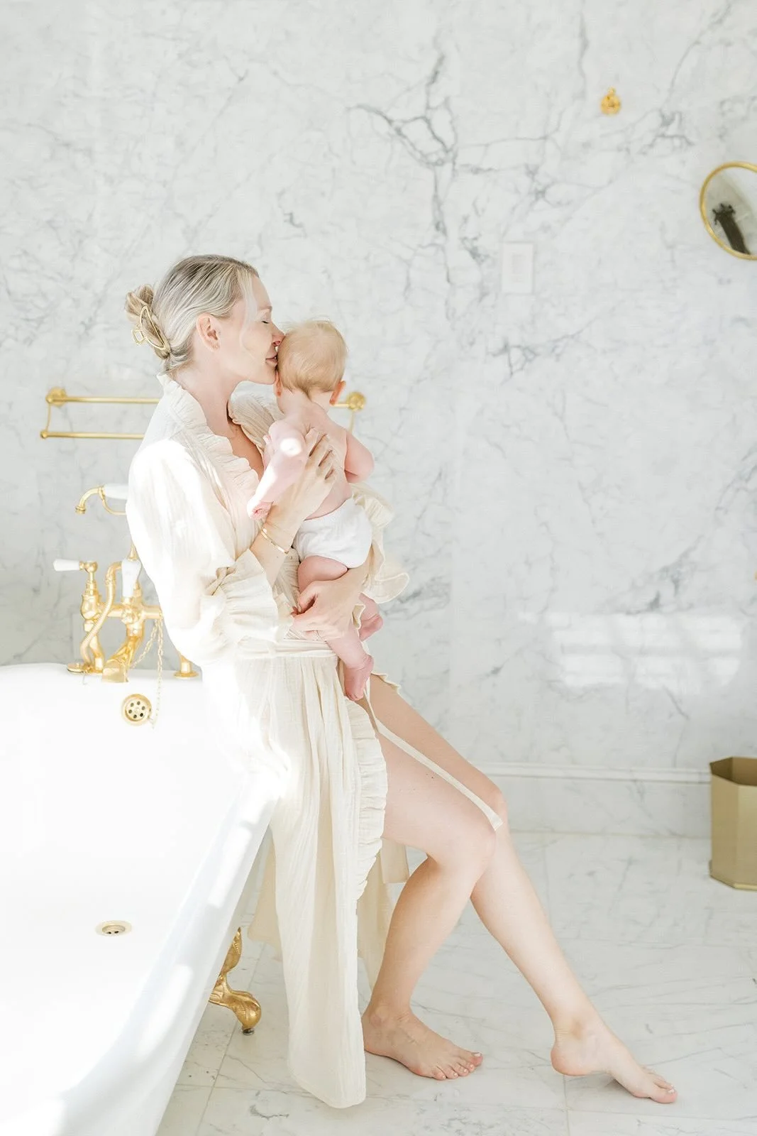 Mother holding baby while sitting on the edge of the tub in the natural light - Raleigh Newborn Photographer