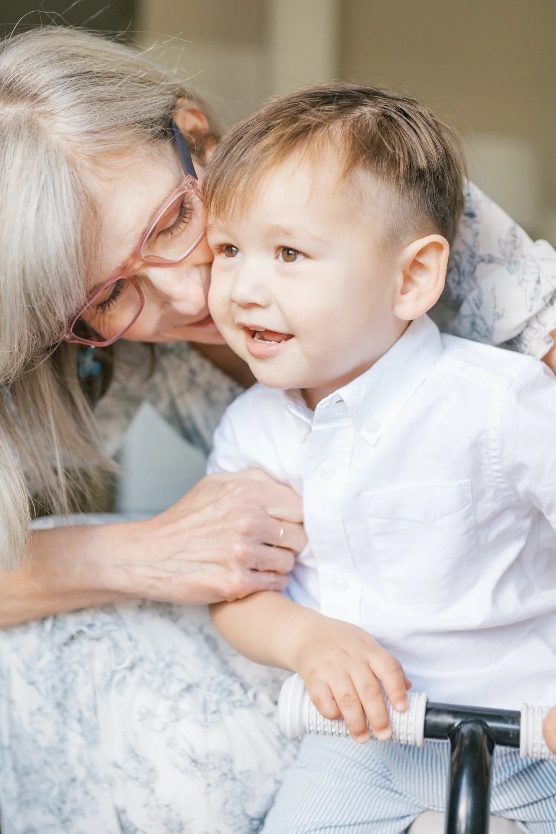 Close up from a grandparent photoshoot of a grandmother leaning in to kiss her smiling grandchild, highlighting their loving bond.