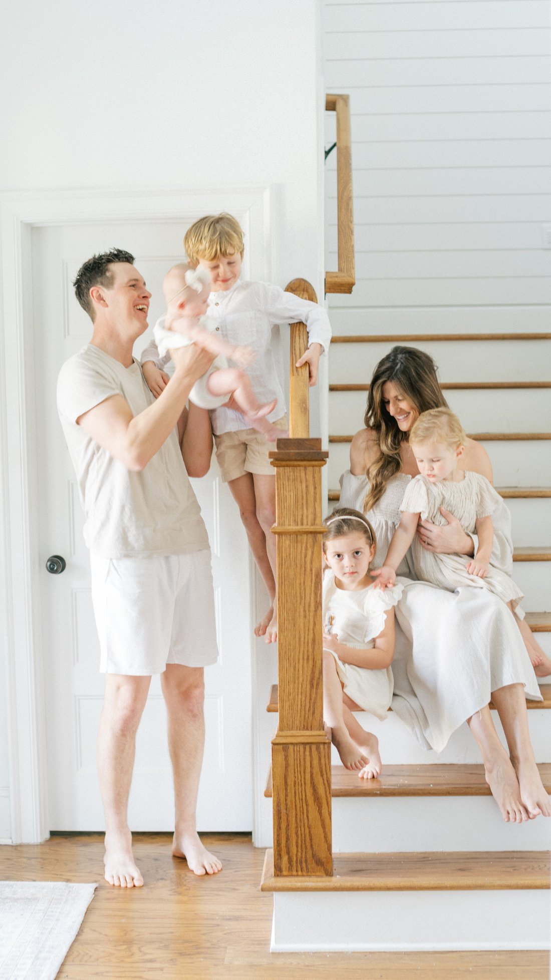 Light-filled family portraits on the staircase featuring parents and four young children in a candid, relaxed setting.