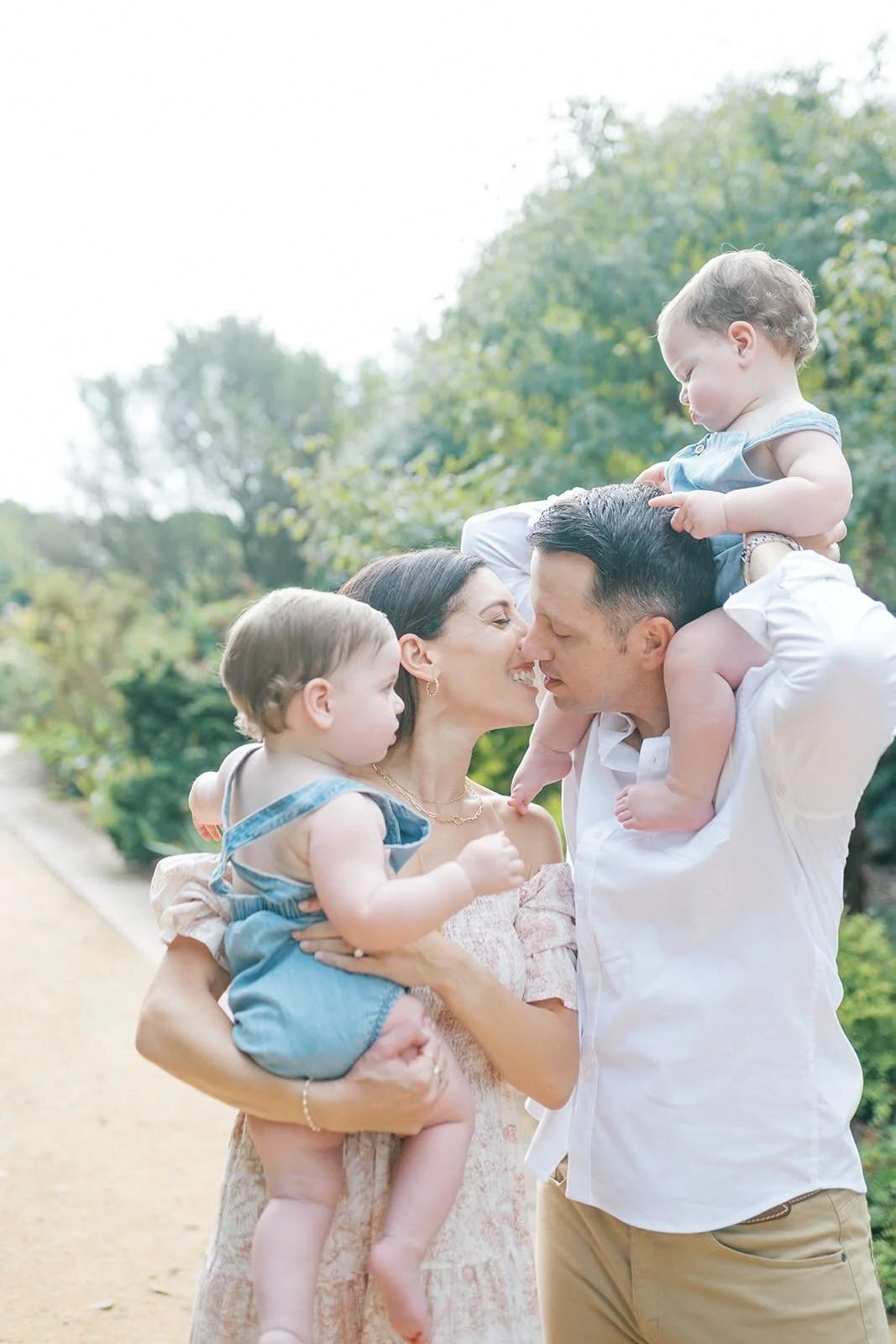 Mom and Dad kissing while holding their sons - Raleigh Newborn Photographer