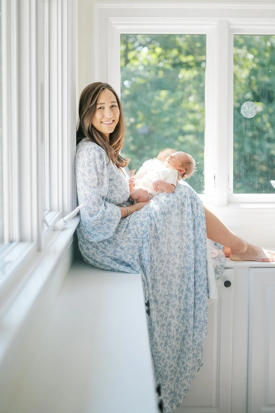 Mother holding baby boy in the natural light while looking at the camera - Raleigh Newborn Photographer