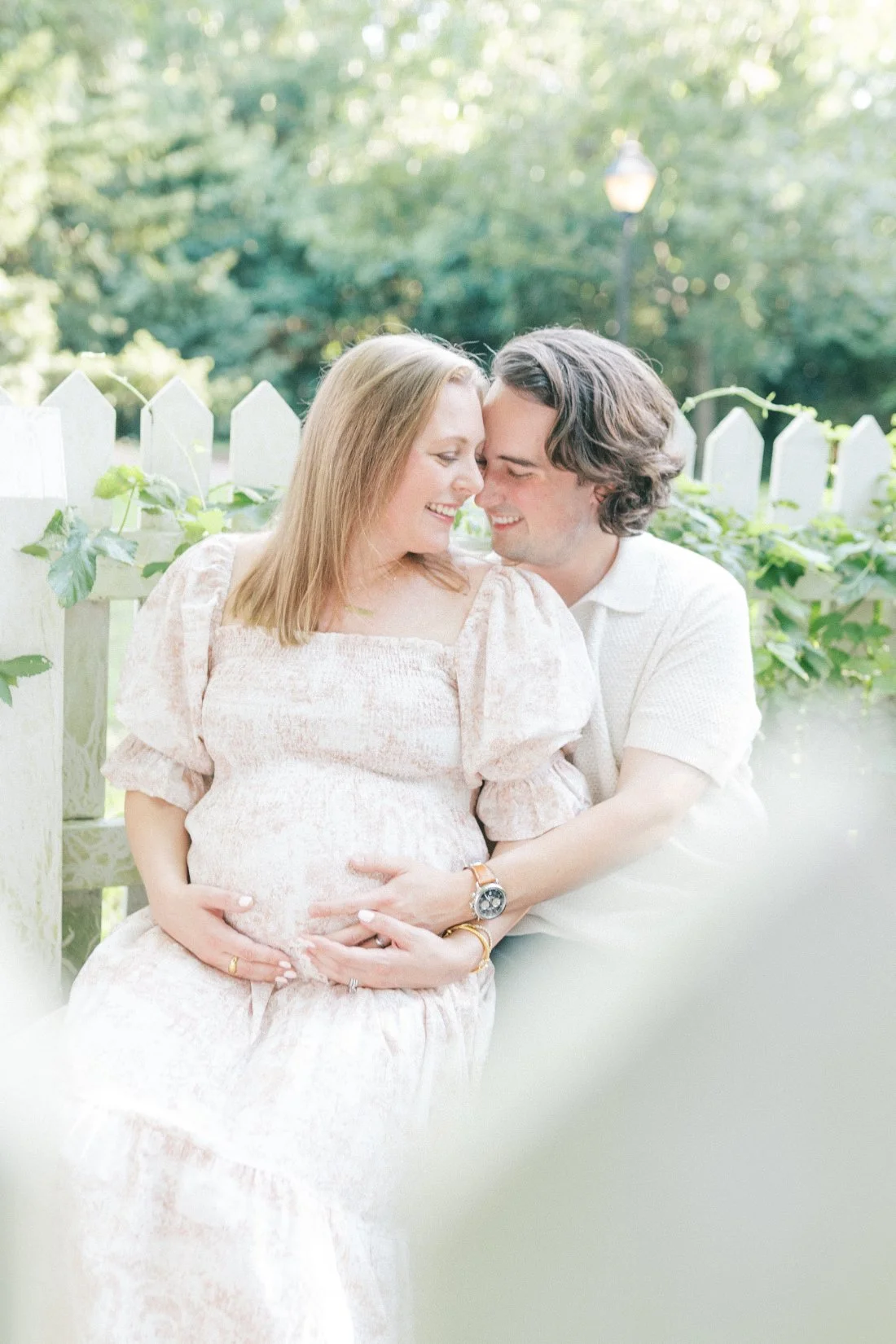 Expectant parents sitting together and holding baby bump during romantic pregnancy announcement photo ideas session in Raleigh NC.
