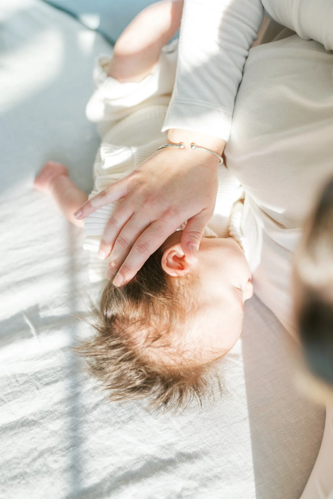 Close-up of a mother gently cradling her newborn’s head while nursing, with soft natural light highlighting the baby’s hair and skin — a tender moment captured through candid family photos.