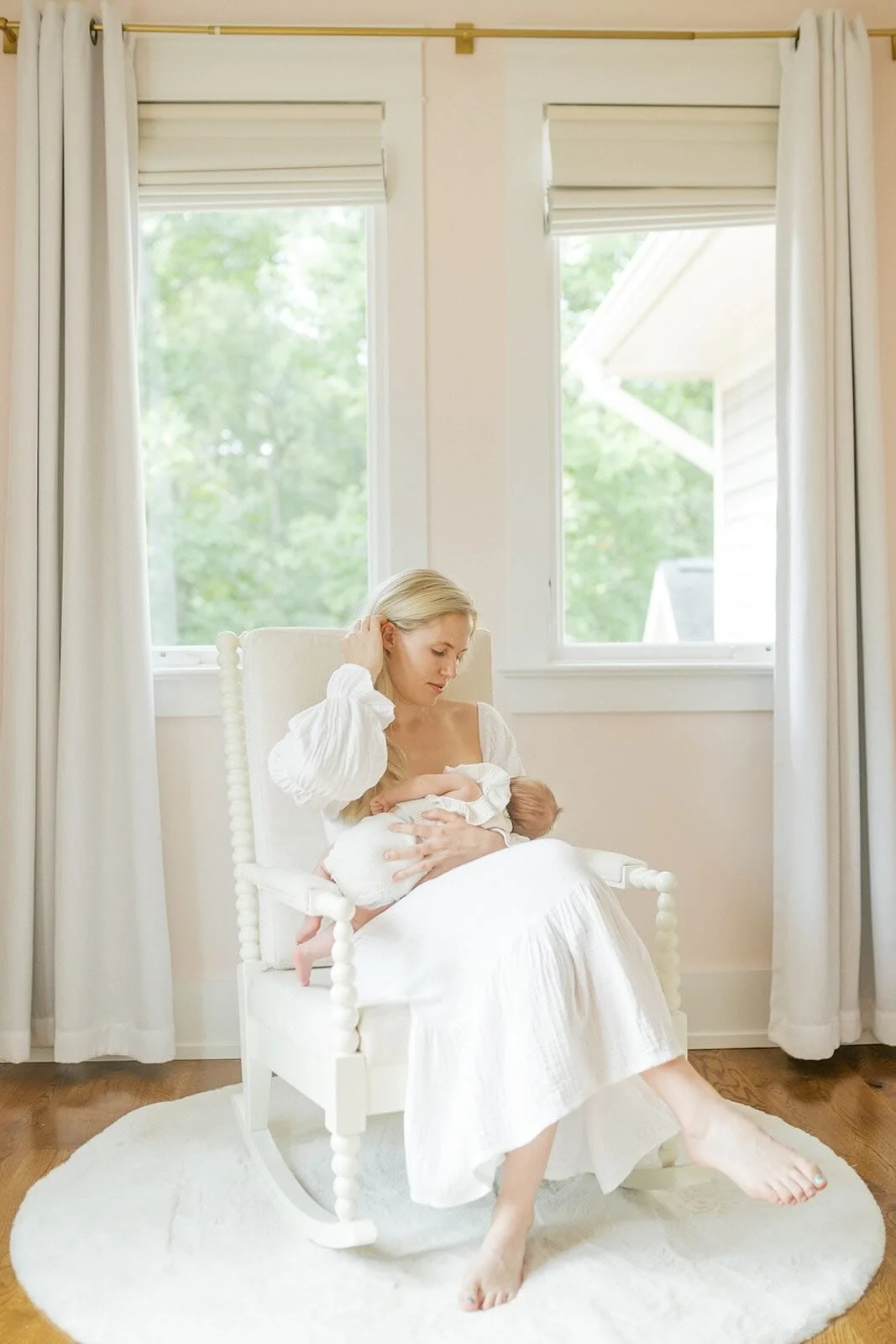 Mother nursing baby in a rocking chair in front of the natural light - Raleigh Newborn Photographer