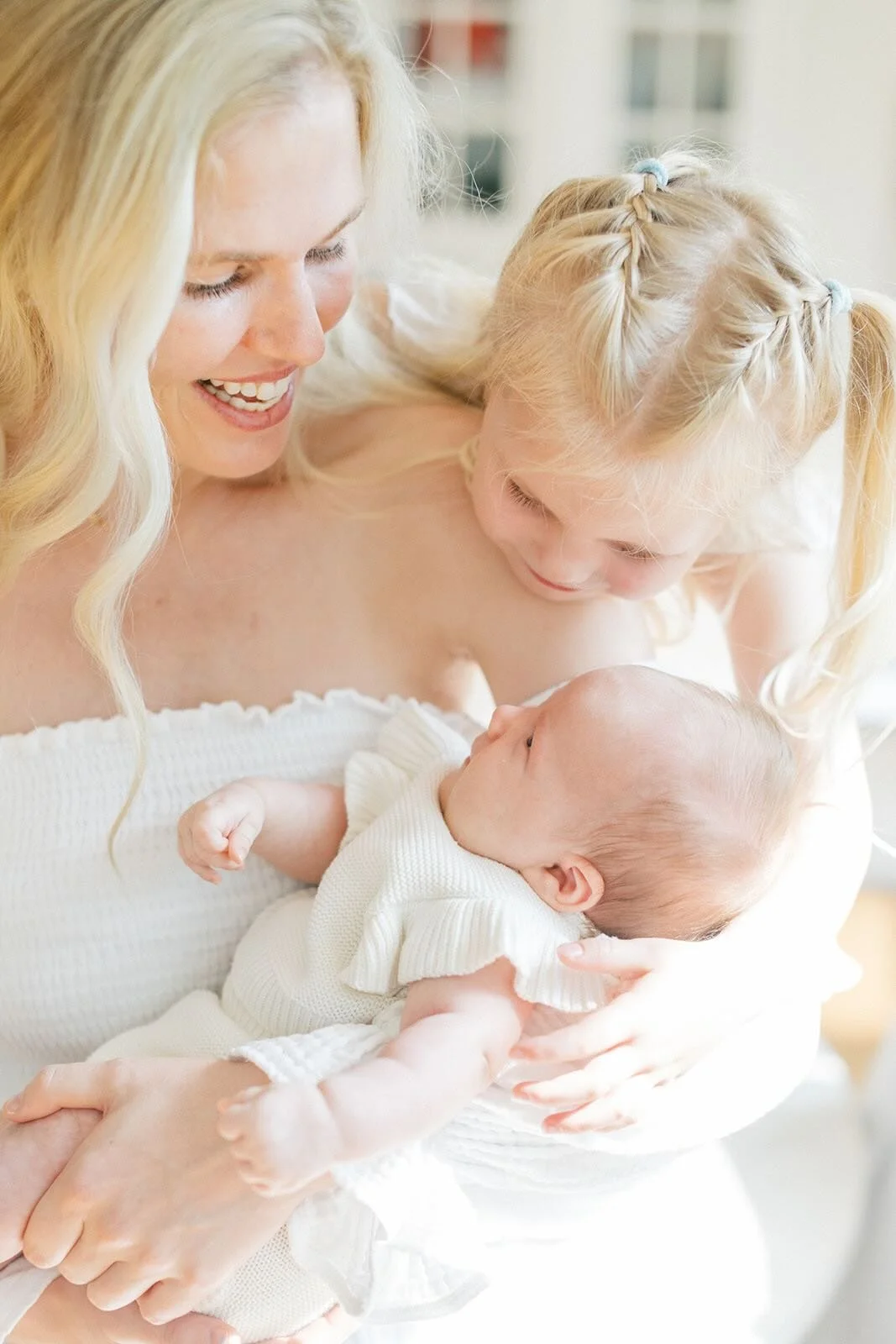 Mother holding baby while big sister looks on lovingly - Raleigh Newborn Photographer