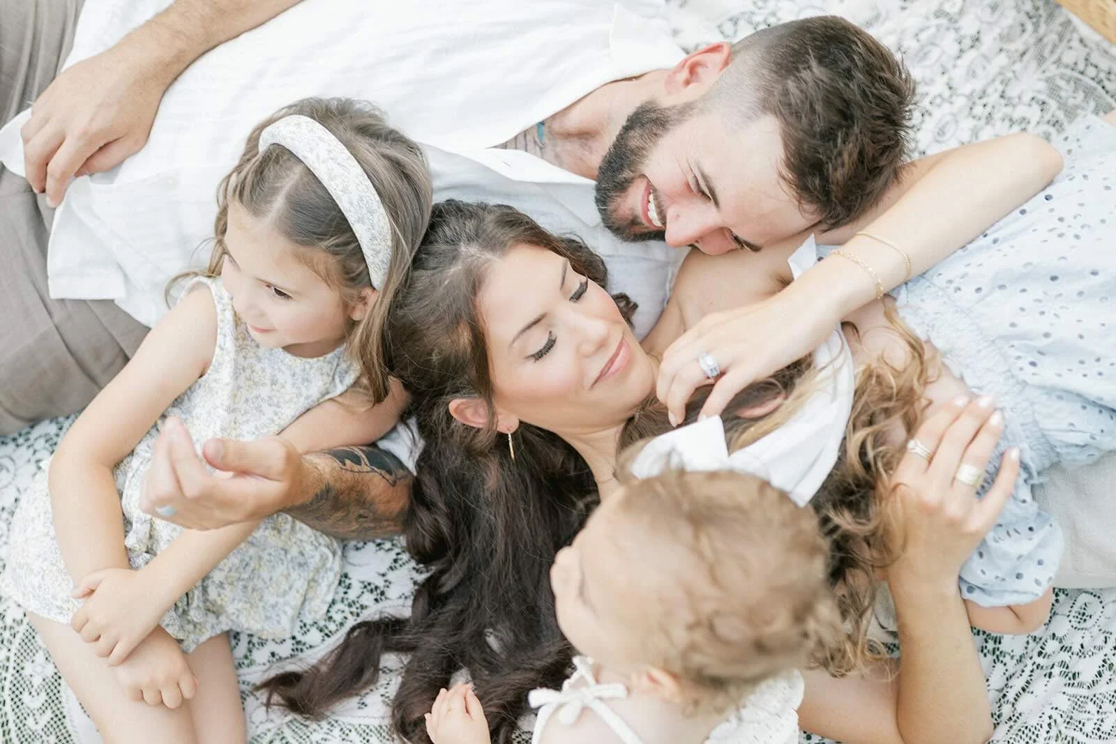 Family snuggles laying on a blanket outside in the natural light - Raleigh Newborn Photographer