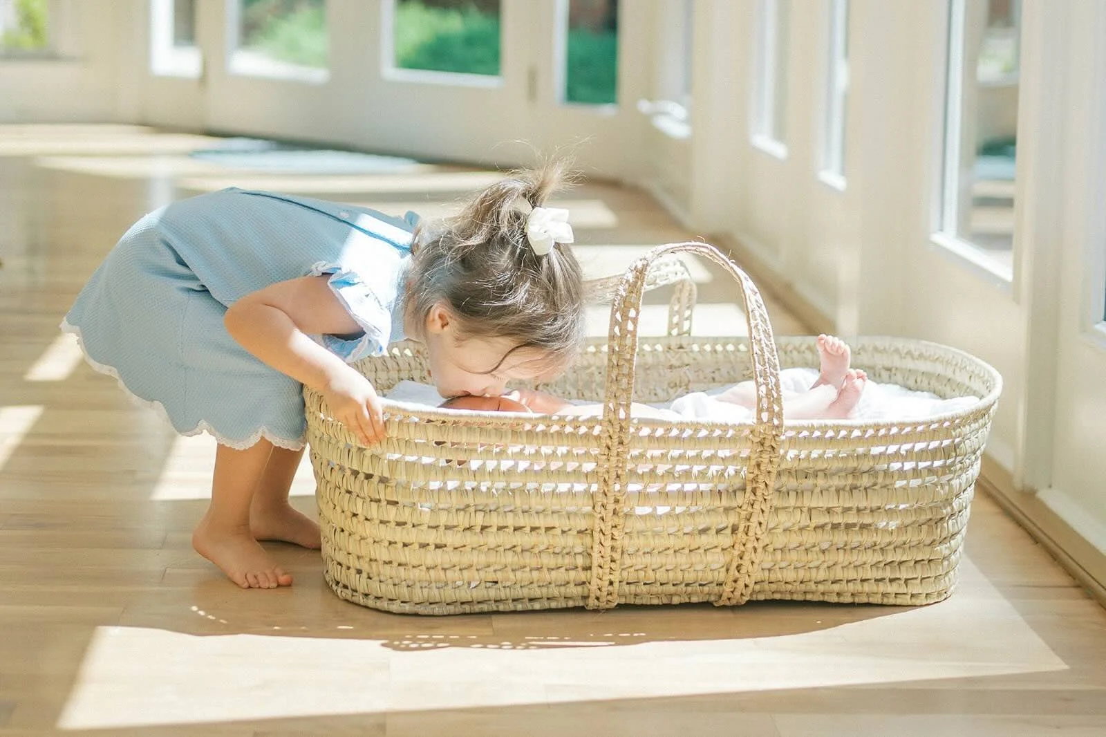 Big sister giving baby brother a kiss in the bassinet - Raleigh Newborn Photographer