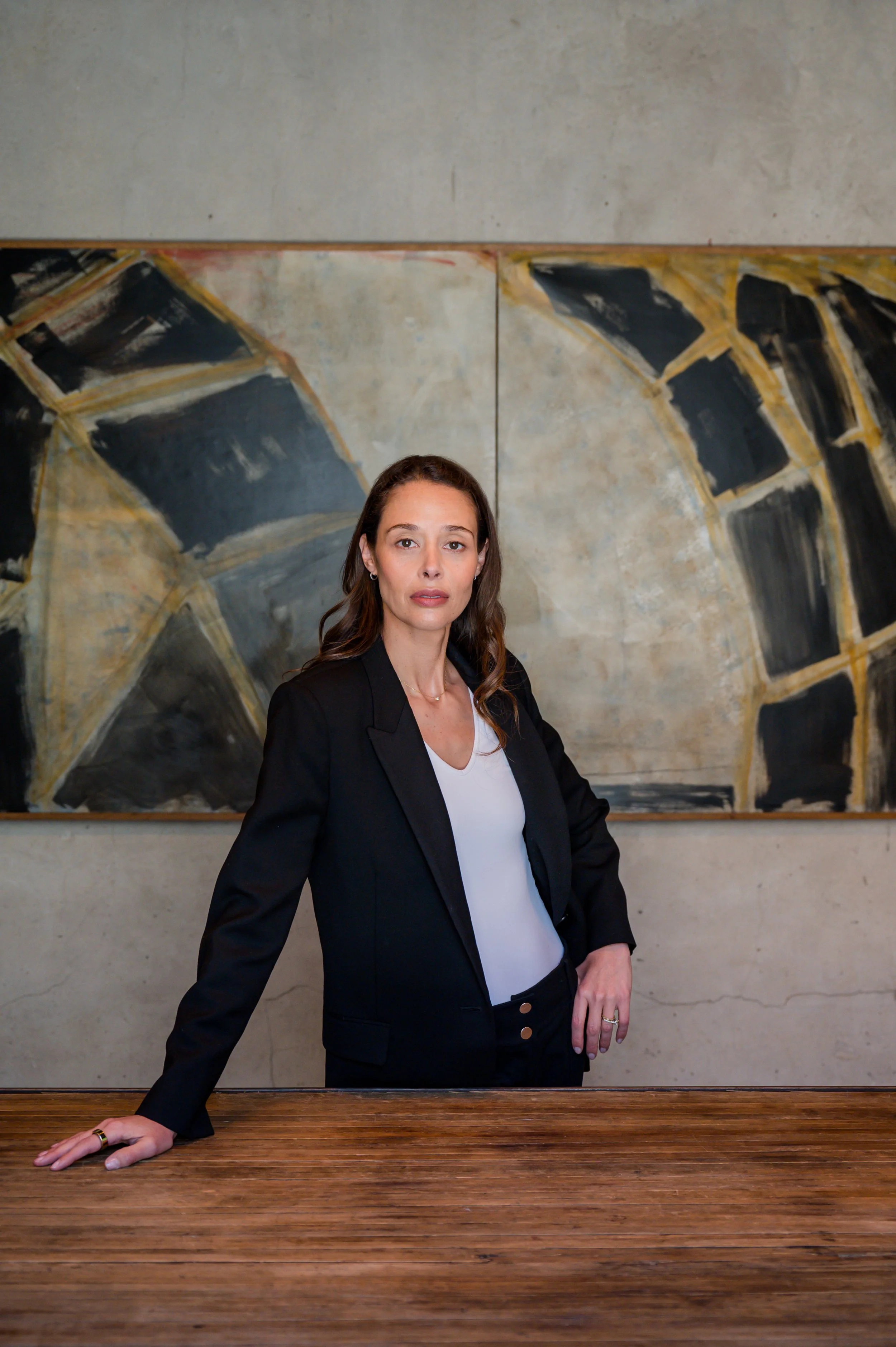 Founder in a black blazer beside a large abstract painting during a personal brand shoot