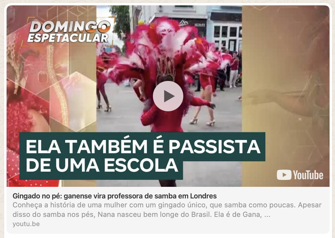 A woman dressed in a red costume with a large feathered headdress performing a samba dance in a street parade.