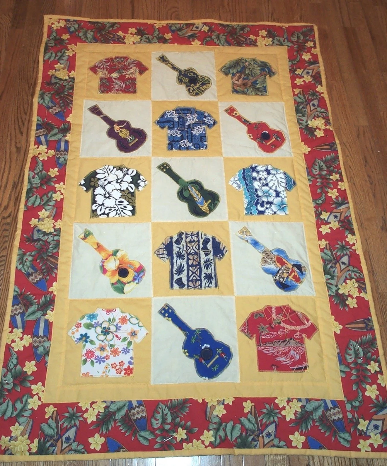 Handmade quilt created by Ross Ozer in 2002 featuring colorful Hawaiian shirts and ukuleles arranged in a repeating geometric grid with a patterned border.