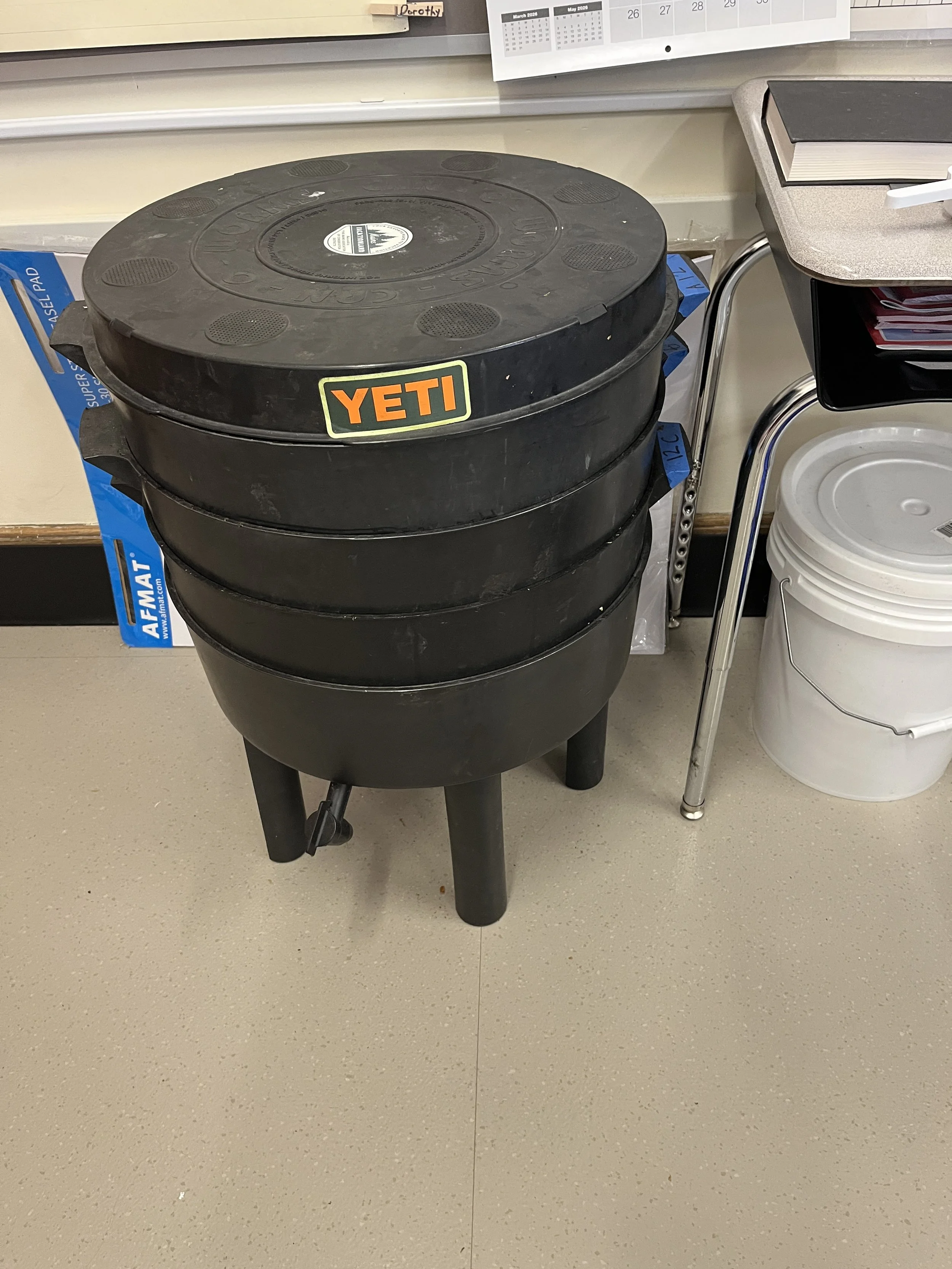 A black, three layered vermicomposting bin in a school classroom.