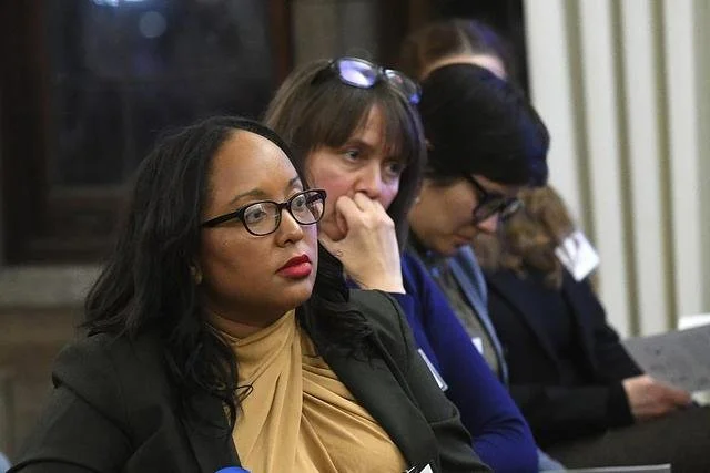 Photo of a group of women in professional clothing, listening intently to off screen speakers