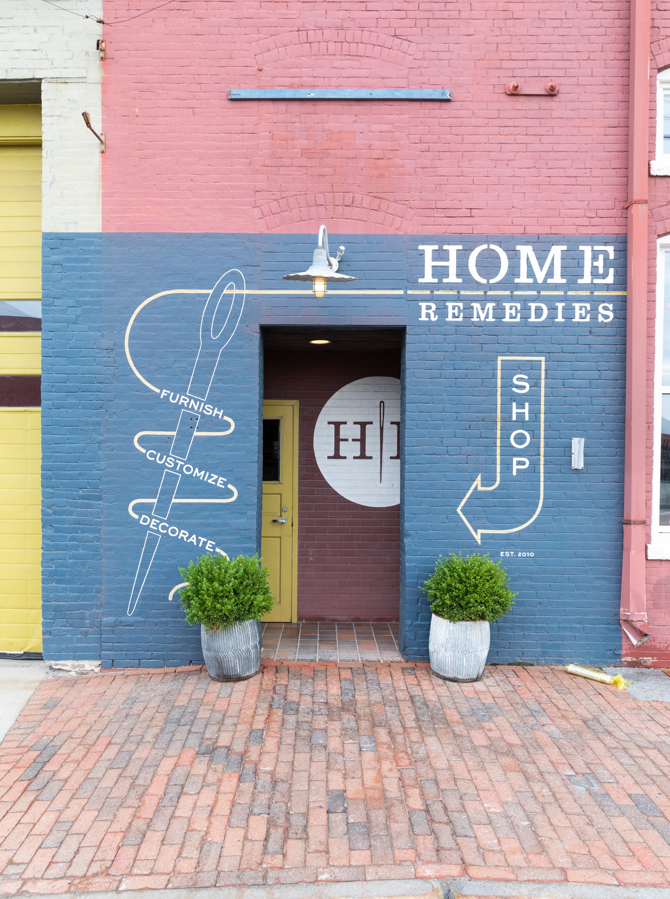 Home Remedies front door with potted plants and graphics painted on brick.