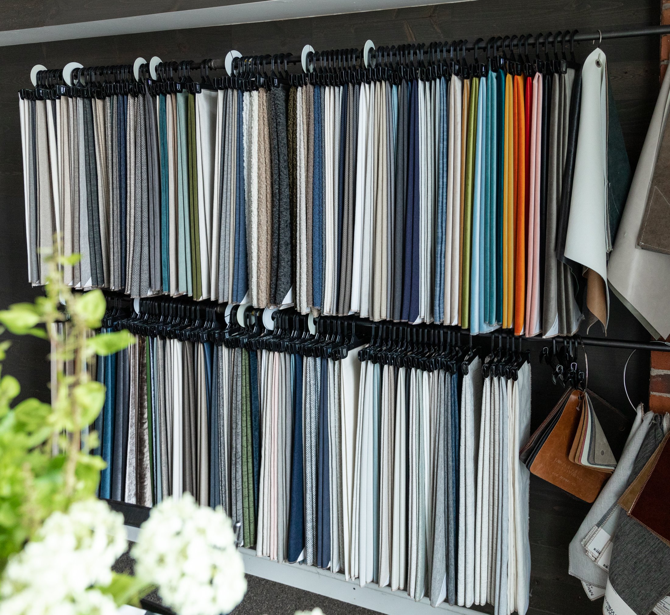 Two rows of fabric samples hanging on wall.