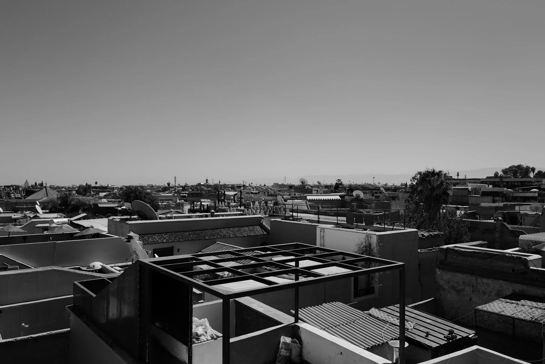 Cityscape view of rooftops with satellite dishes and antenna structures on a clear day.