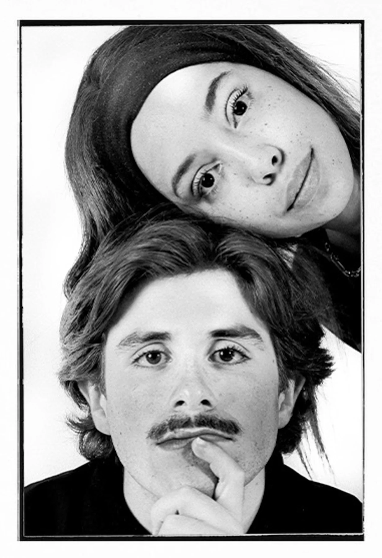 Black and white portrait of a woman with long hair, wearing a headband, looking to the side, and a man with medium-length hair and a mustache, resting his chin on his hand.