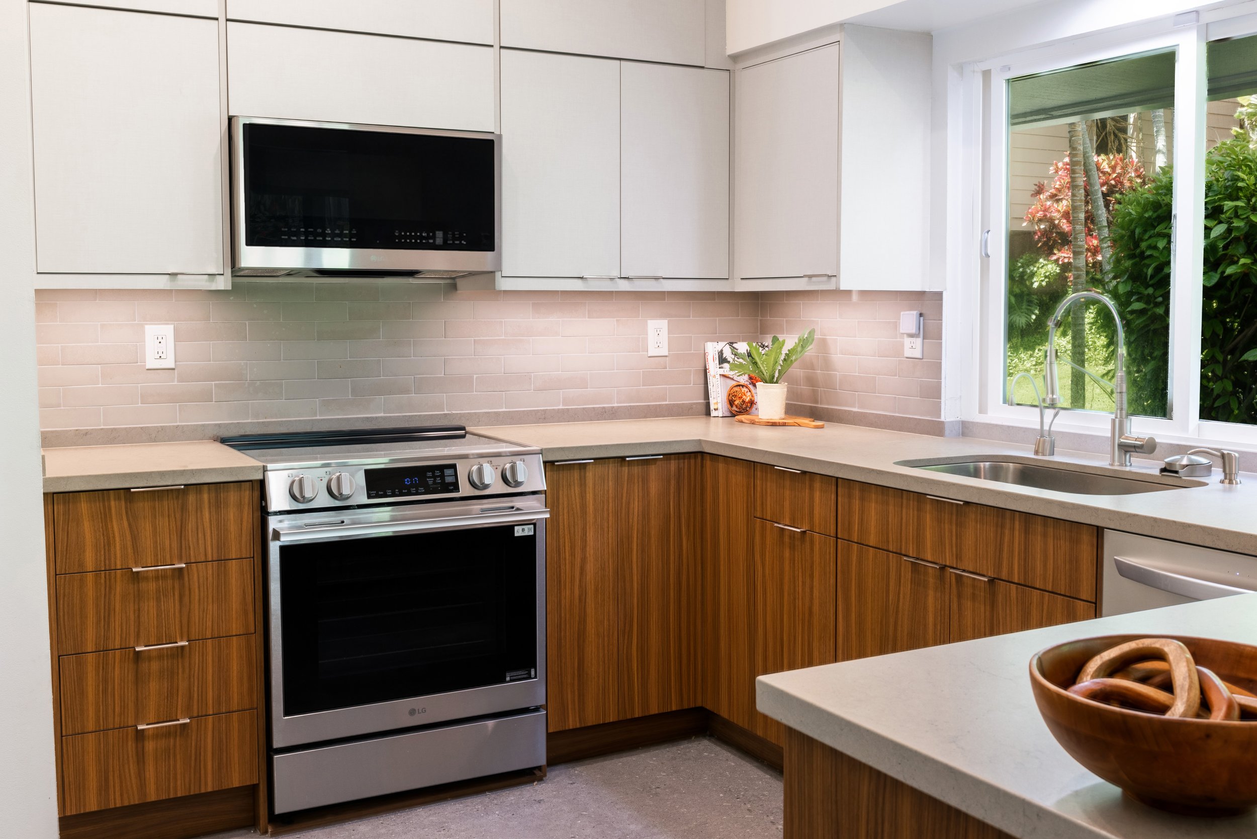 Remodeled kitchen featuring two-tone cabinetry, walnut lower cabinets, white upper cabinets, vaulted ceilings, and custom storage solutions.