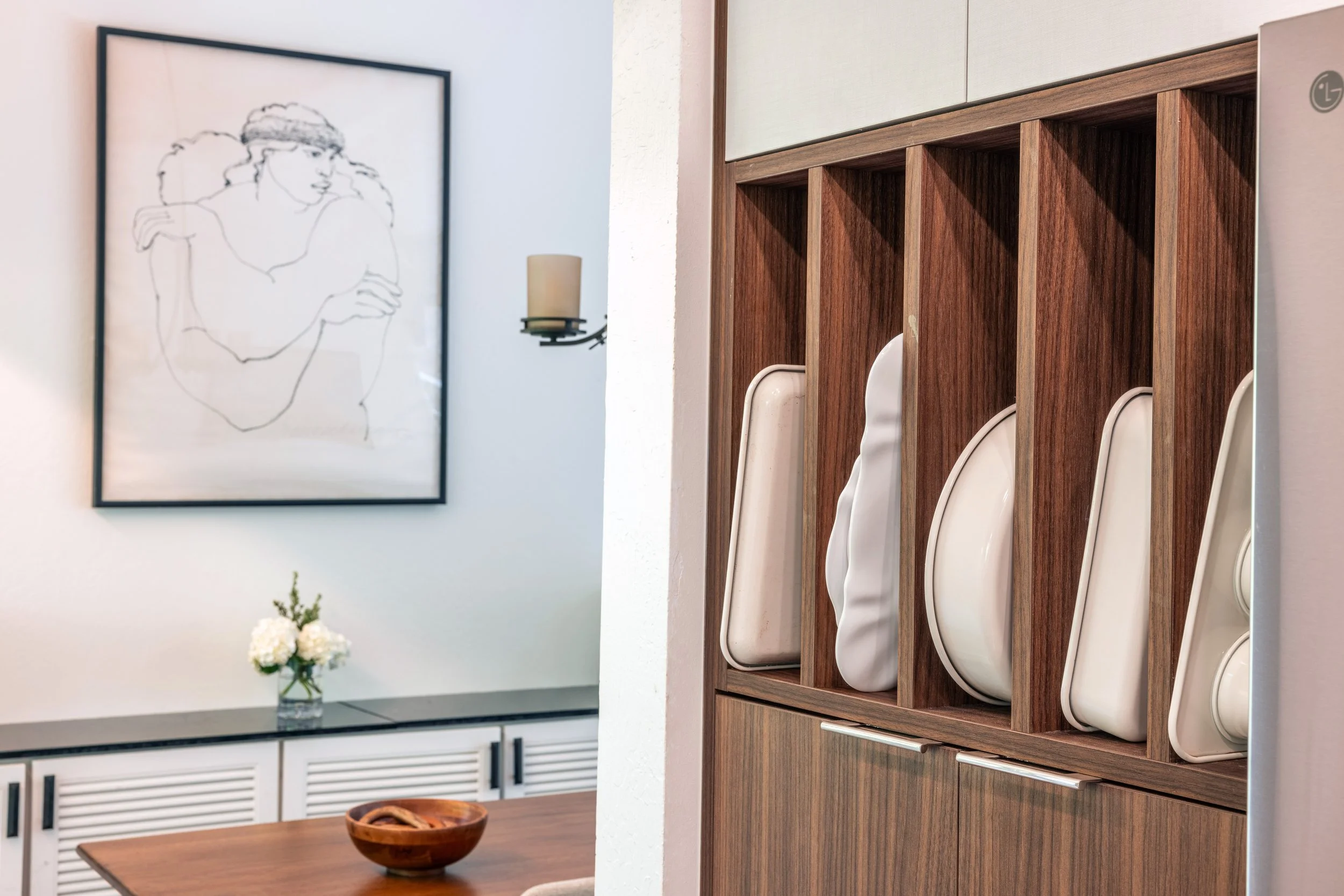 Built-in baking tray organizer integrated into custom walnut cabinetry for convenient kitchen storage.