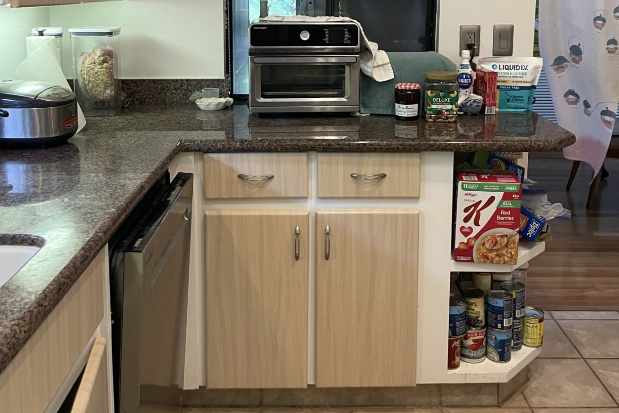 Original kitchen before renovation featuring aging wood cabinetry, dark countertops, tile flooring, and limited storage space.