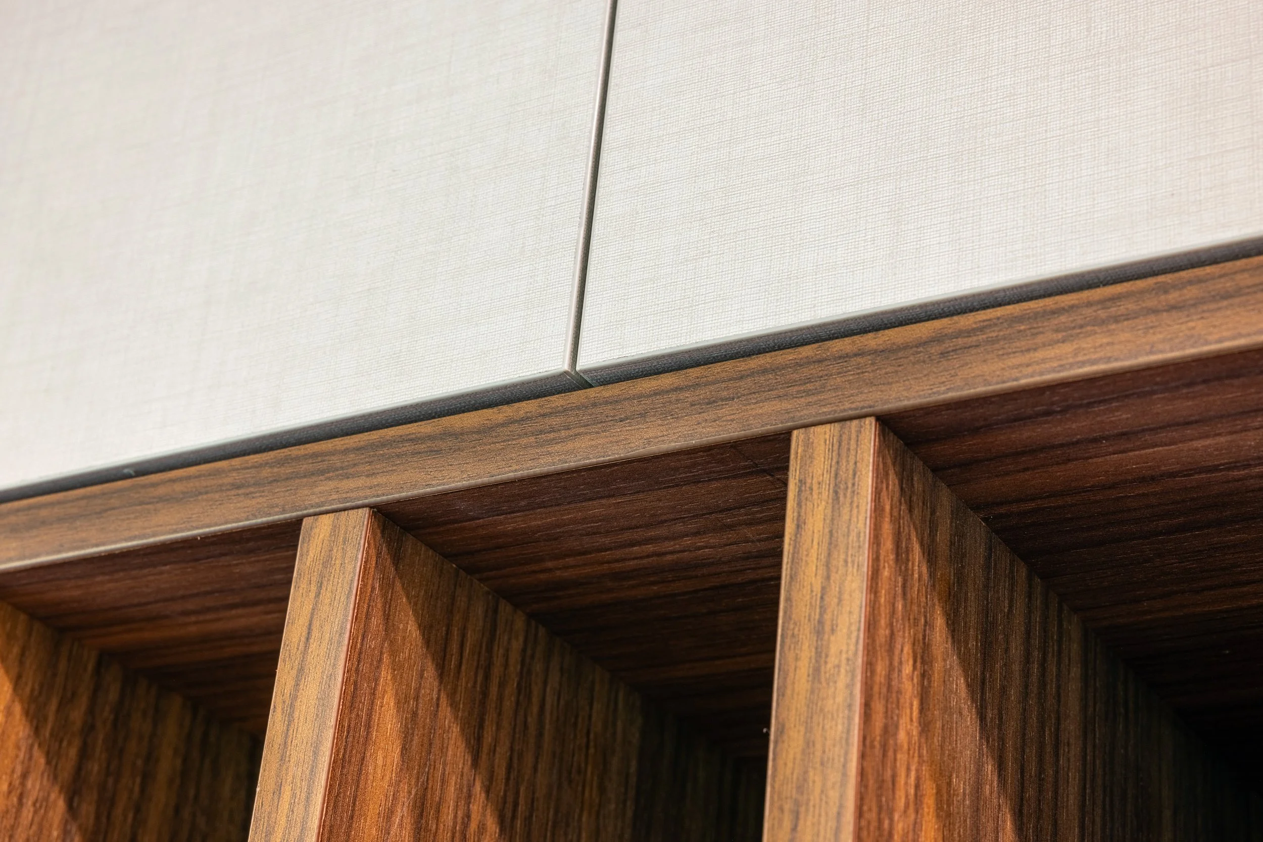 Custom kitchen cabinetry combining warm walnut lower cabinets with light upper cabinets to create an open and inviting space.