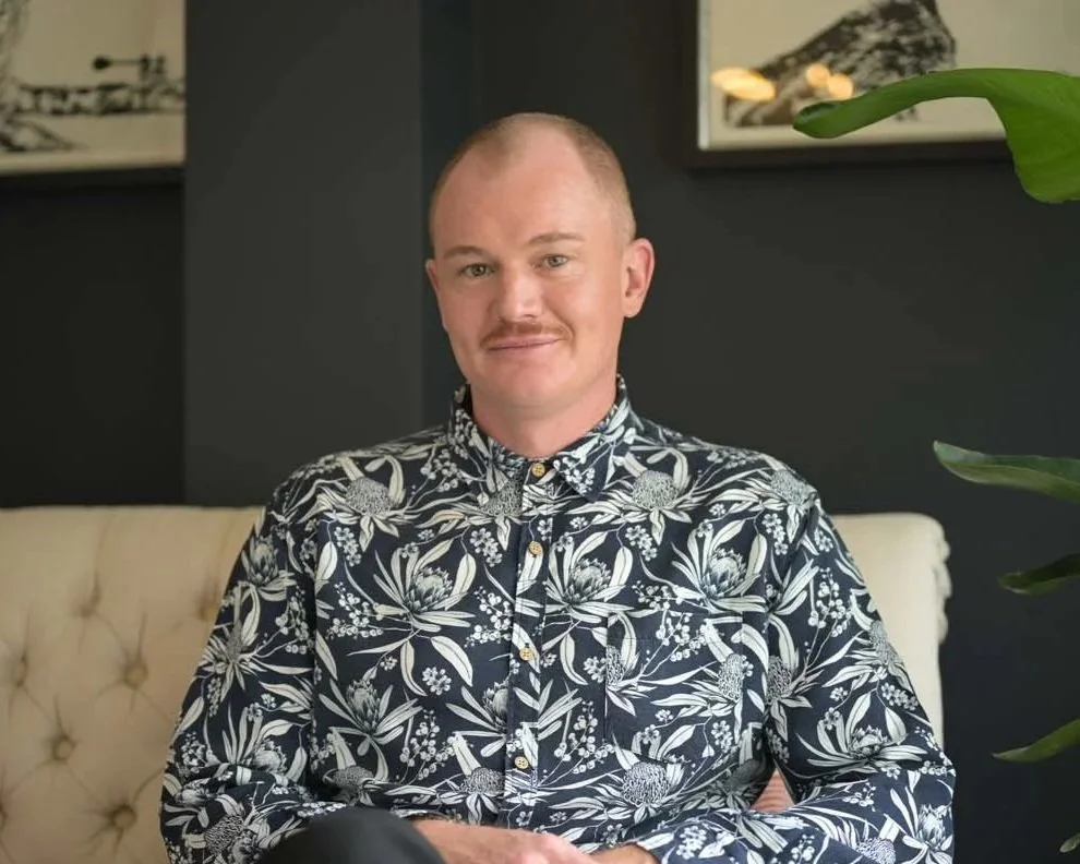 Ben Gibson, smiling and soulful, with lush bushland behind him