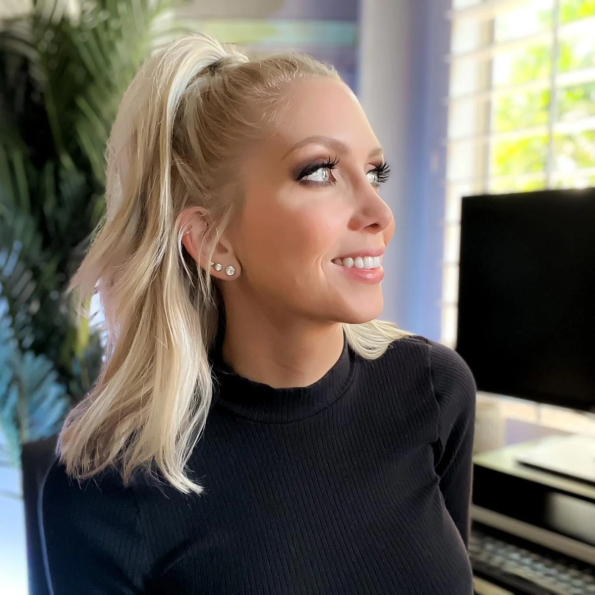 Blond woman in a black turtle neck smiling.