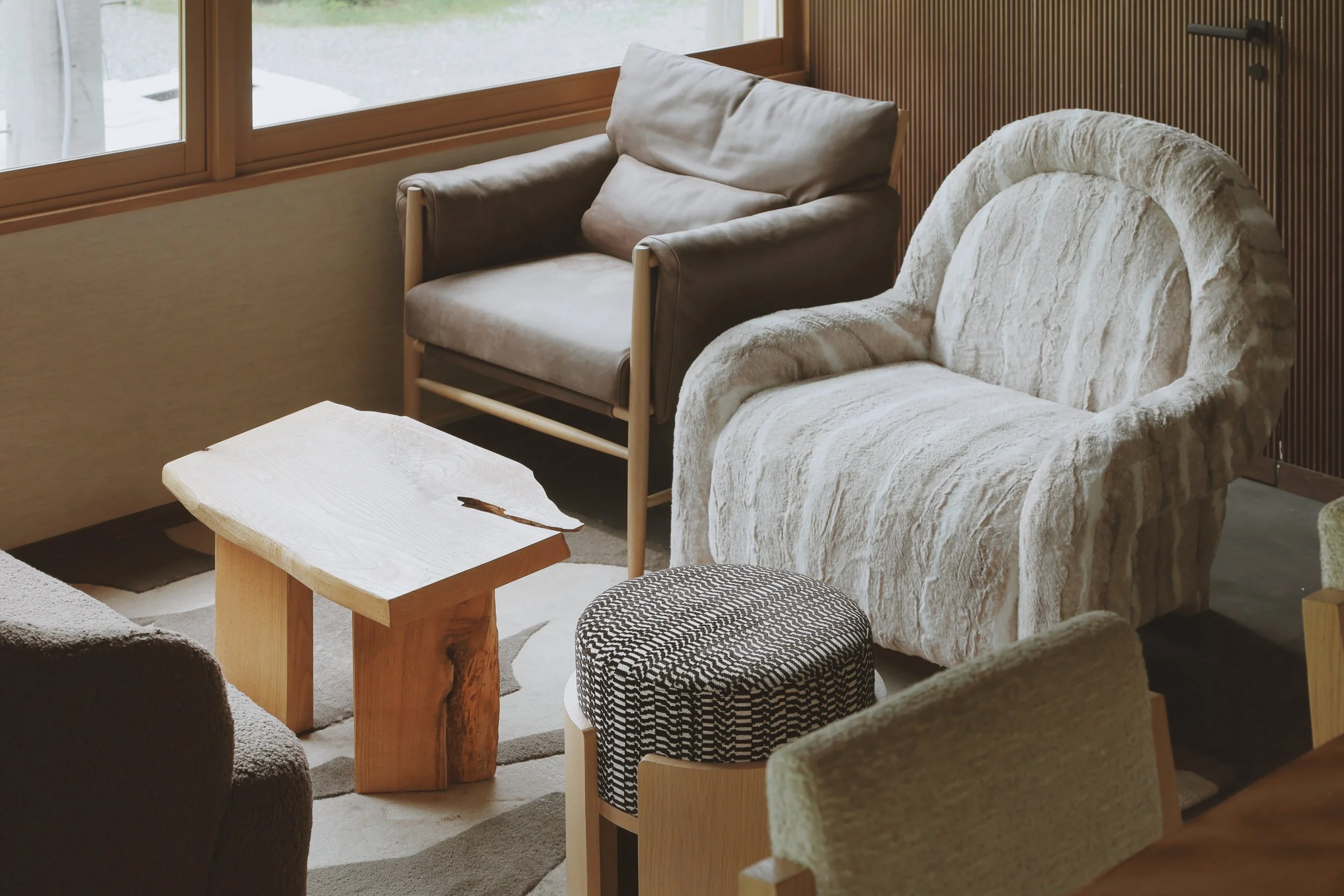 Living room with beige armchairs, a small wooden table, and a window with natural light.
