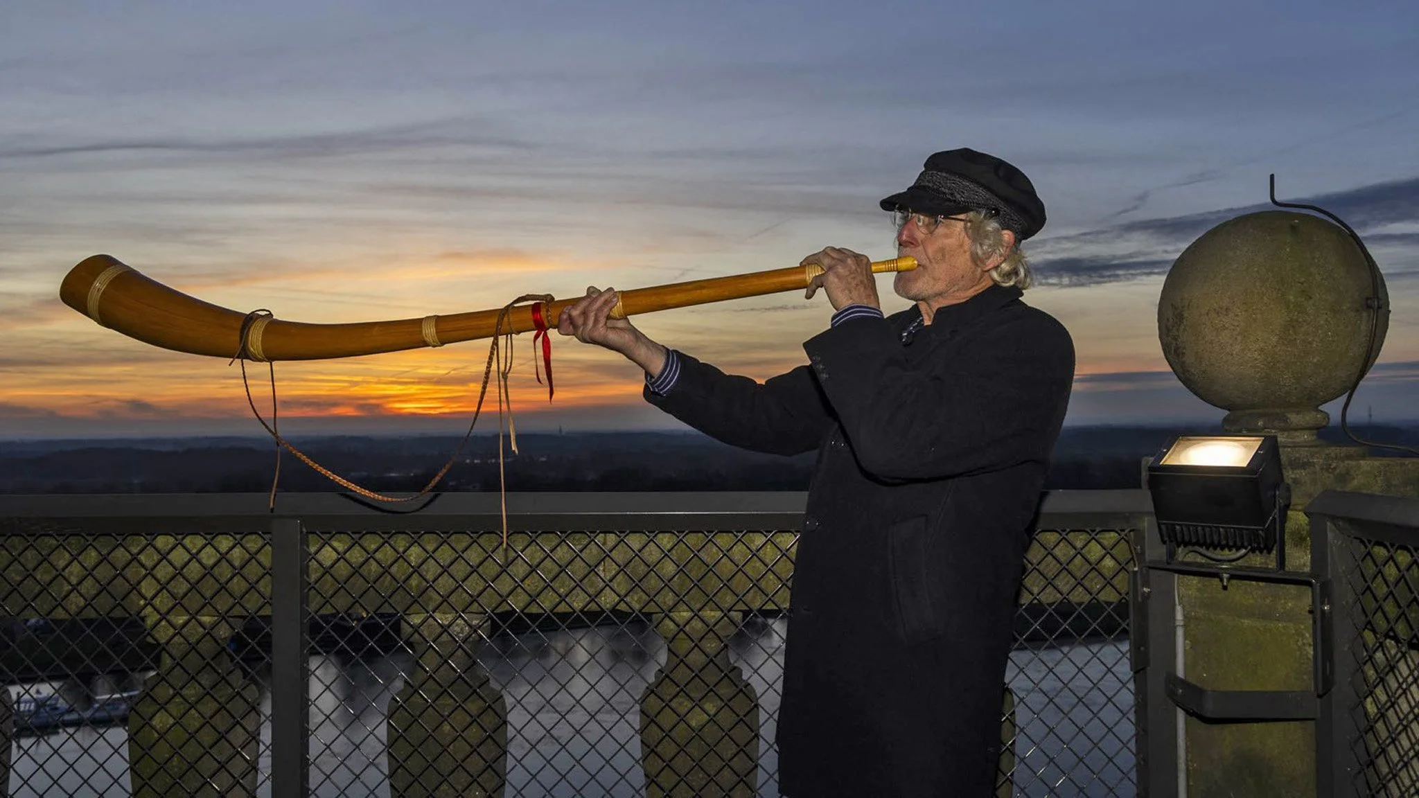Het blazen van de midwinterhoorn vanaf de trans van de Lebuinustoren in Deventer, bij zonsondergang voor de langste nacht (21 december 2025).