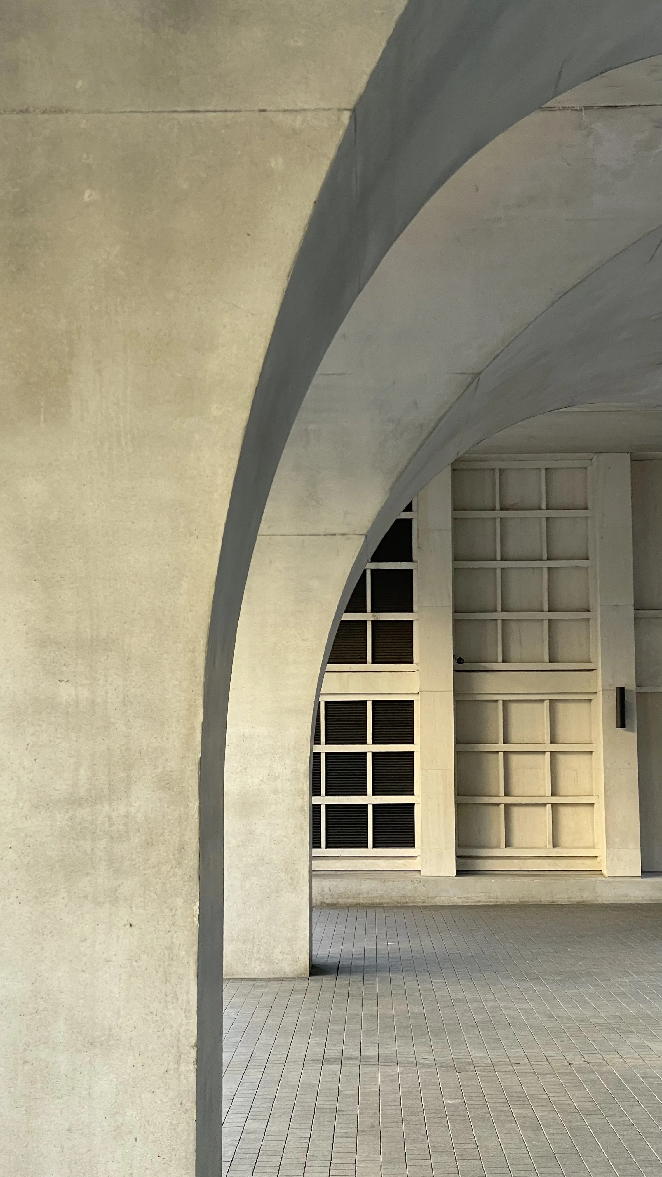 Architectural view of a building with concrete arches and large windows.
