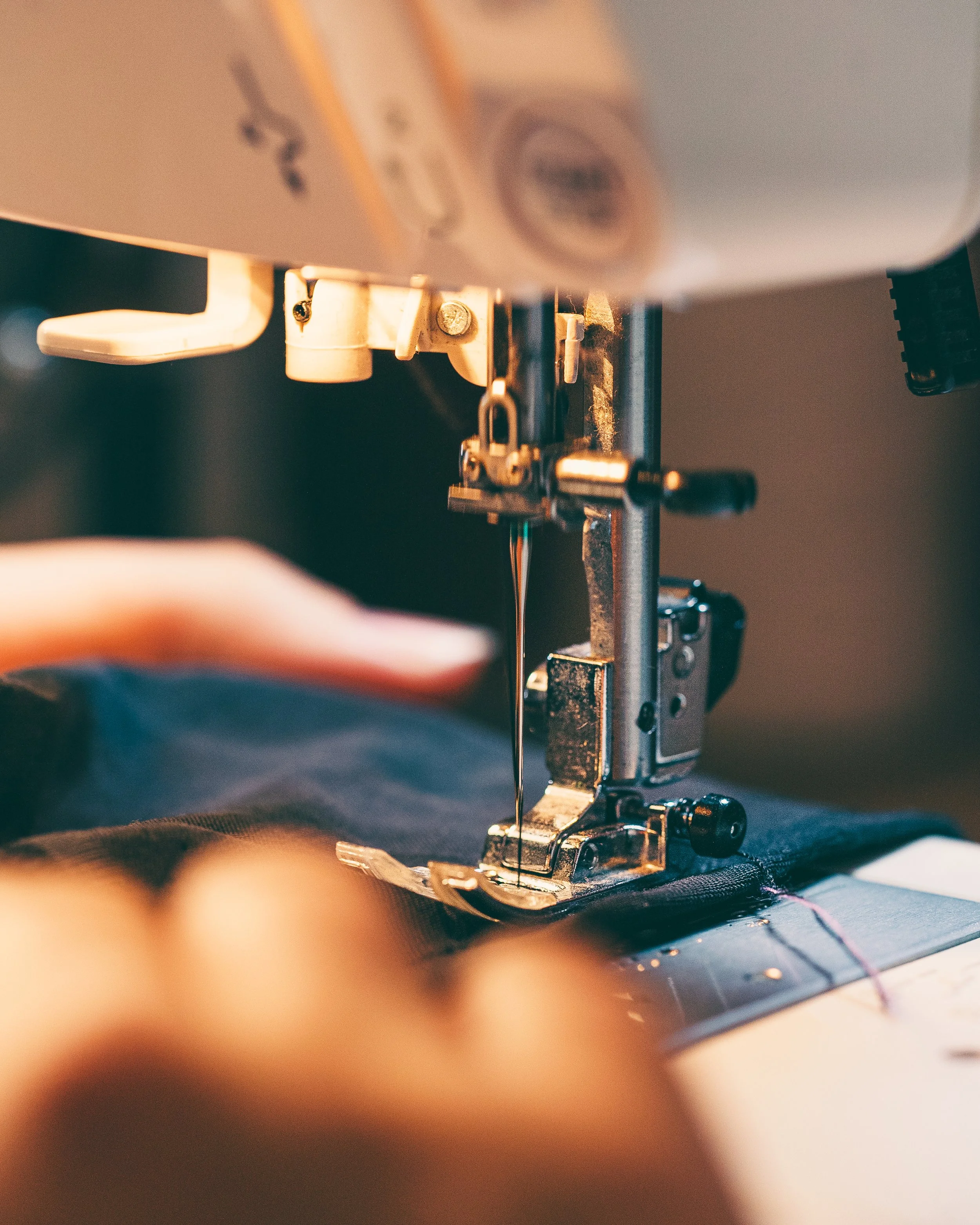 Close-up of a sewing machine's needle stitching black fabric.