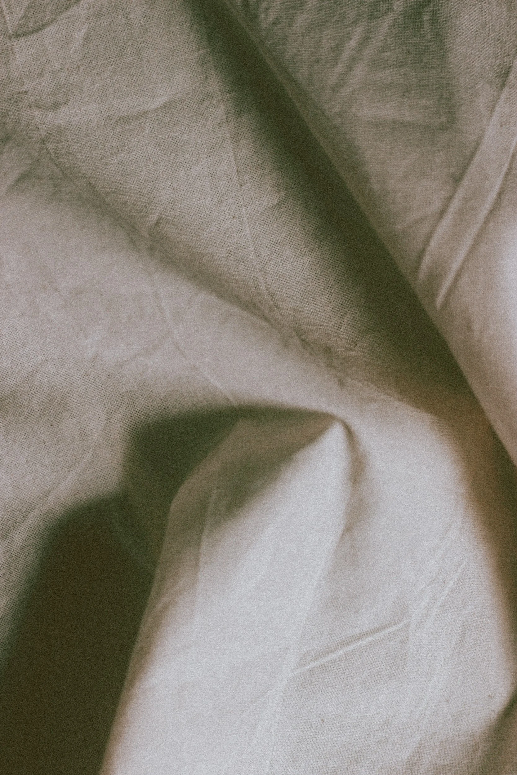 Close-up of beige and off-white fabric with folds and texture.