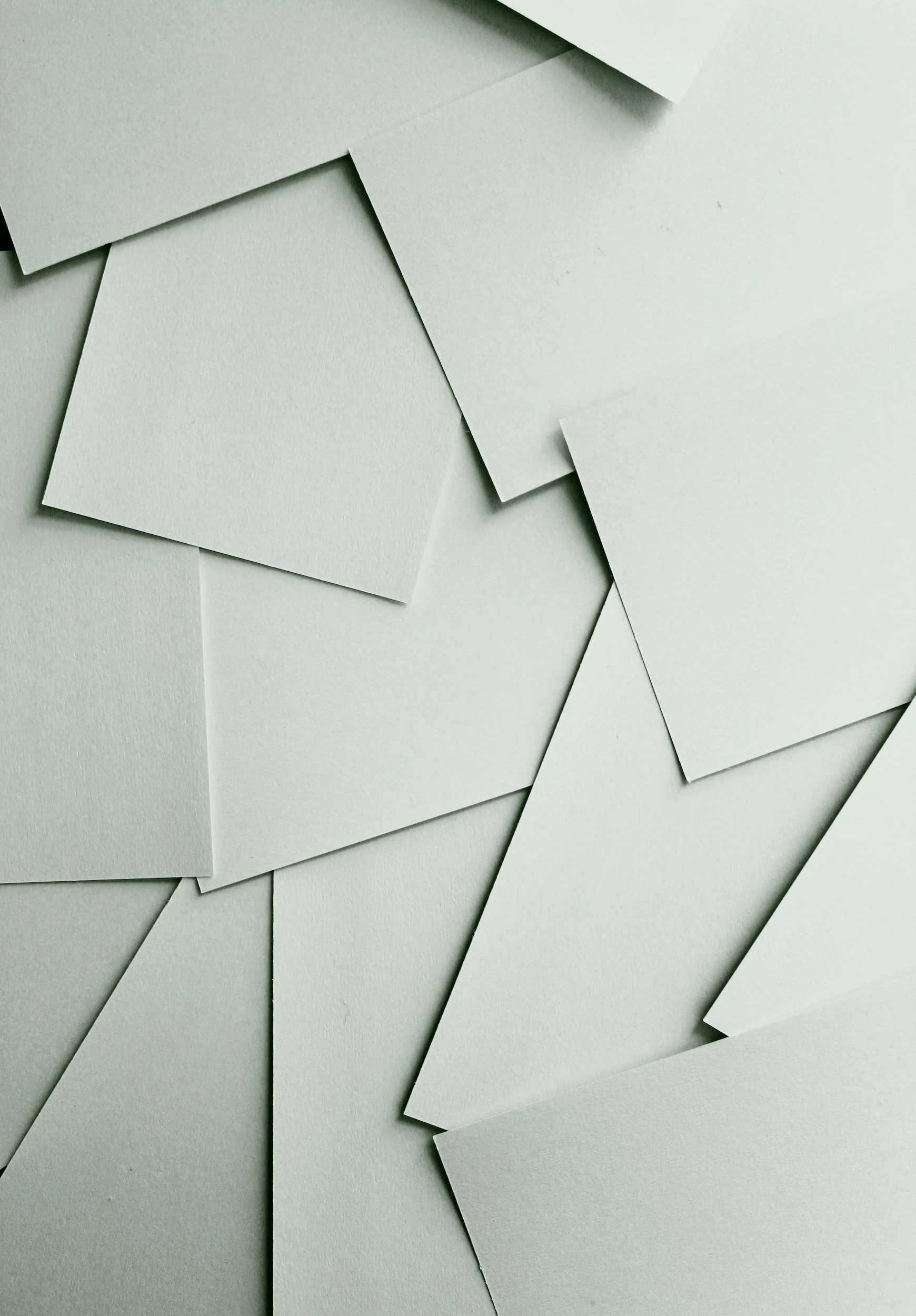 Multiple white textured paper sheets arranged overlapping on a flat surface.