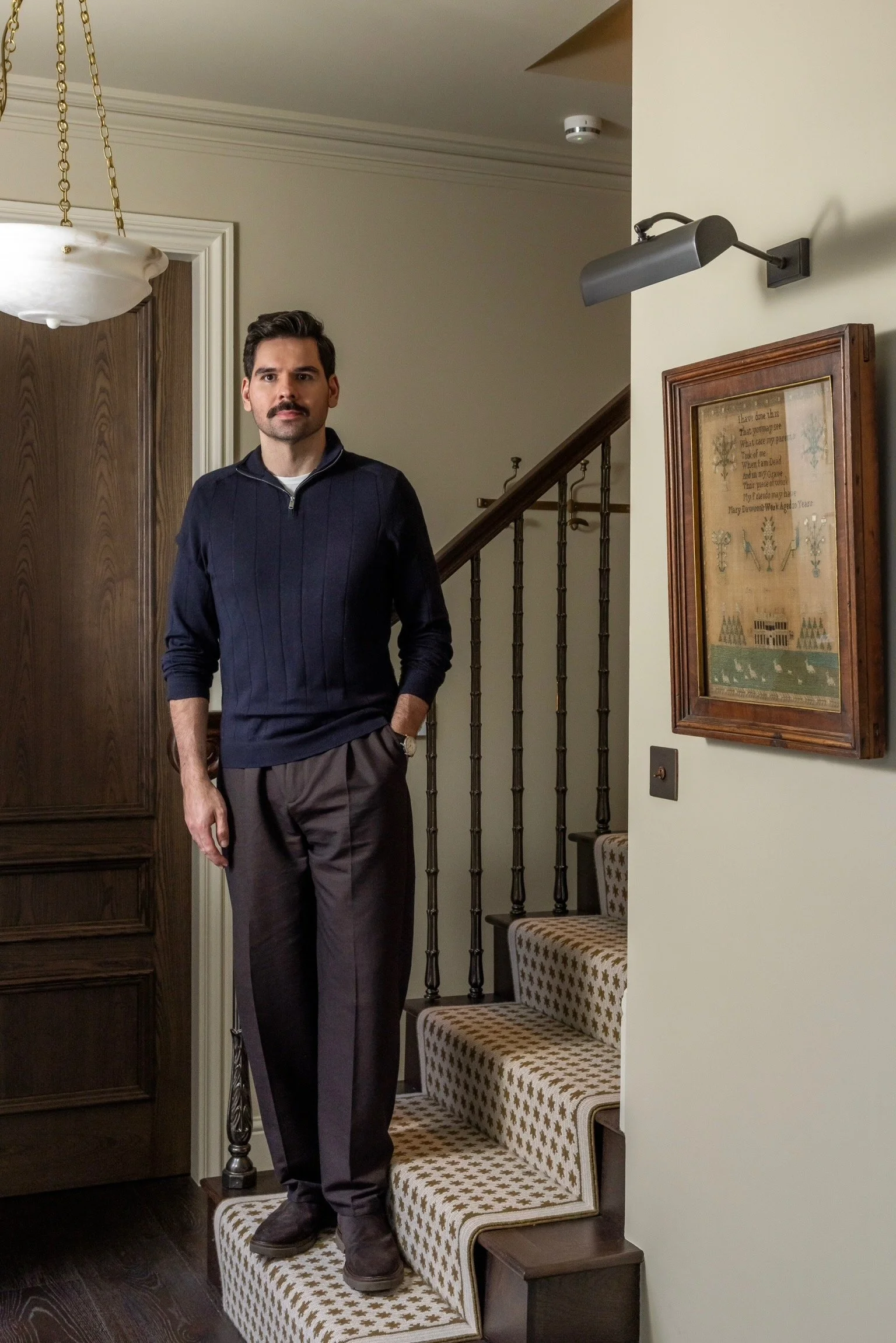Traditional interior designer Joel Azevedo standing on an elegant period staircase in a London home, showcasing historic architecture restoration expertise