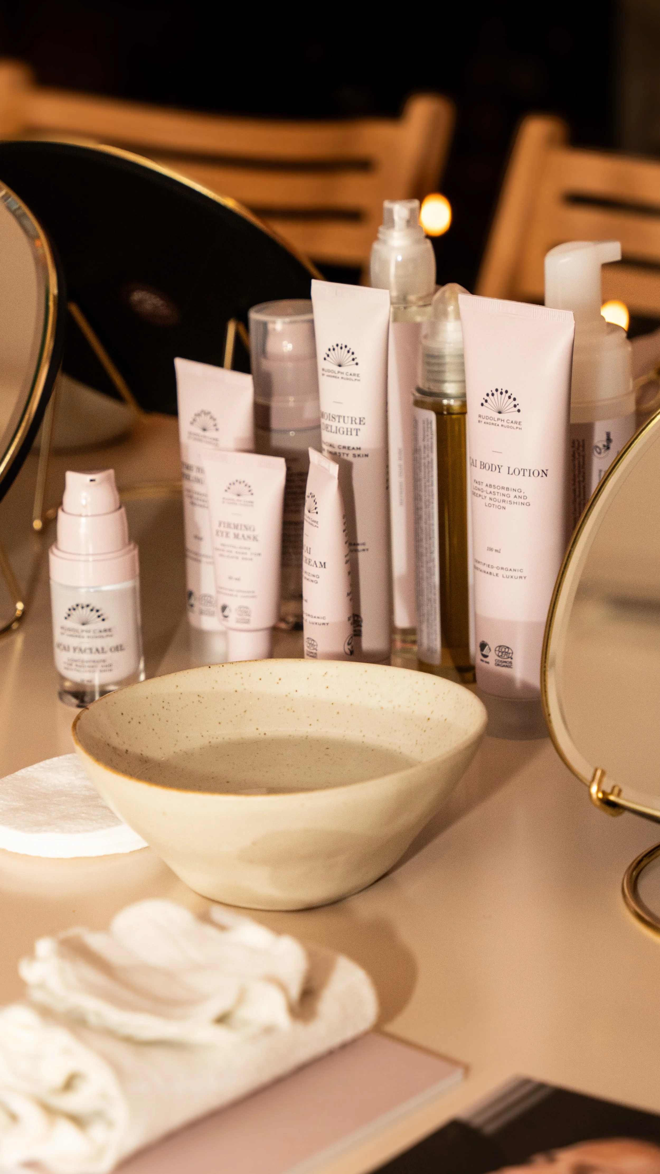Skønhedsprodukter på bordet, herunder lotioner, cremer og øjenmasker, med spejle i baggrunden.