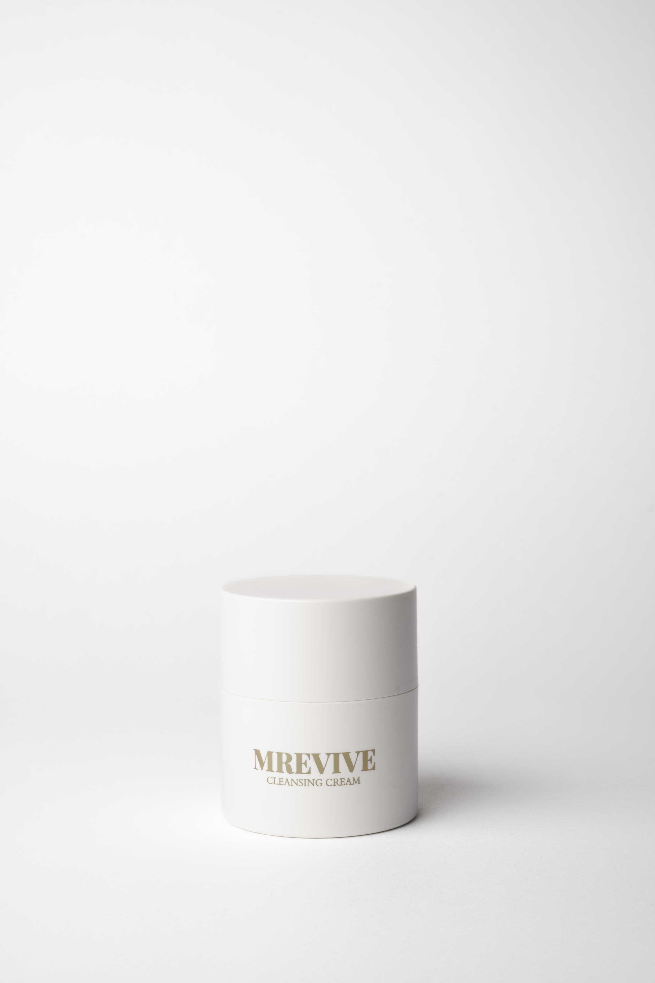 Hvid kosmetikbeholder med guldskrift 'MREVIVEE' og 'Cleansing Cream' på en hvid baggrund.