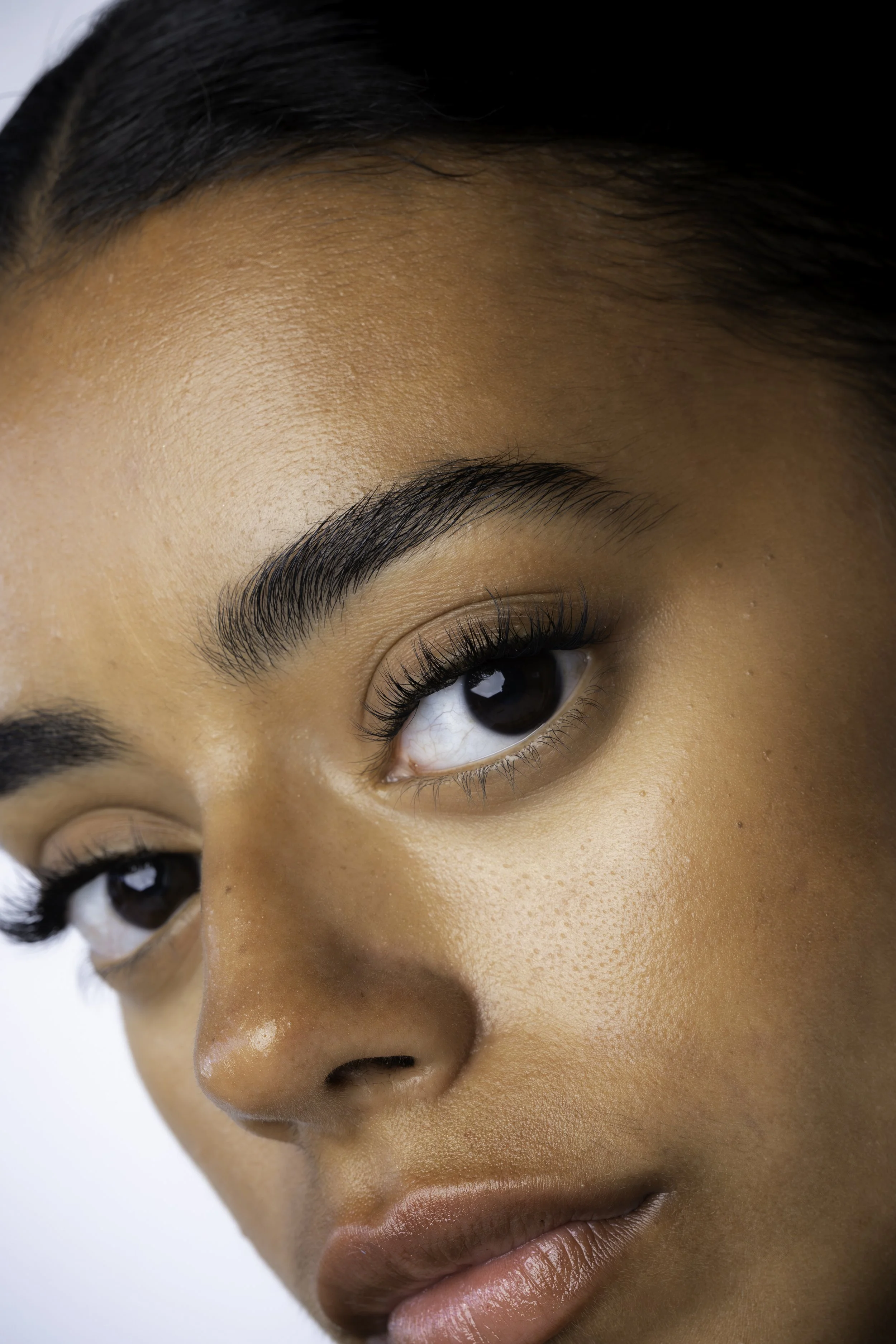 Nærbillede af en kvindes ansigt med fokus på øjenområde og velplejede øjenbryn.