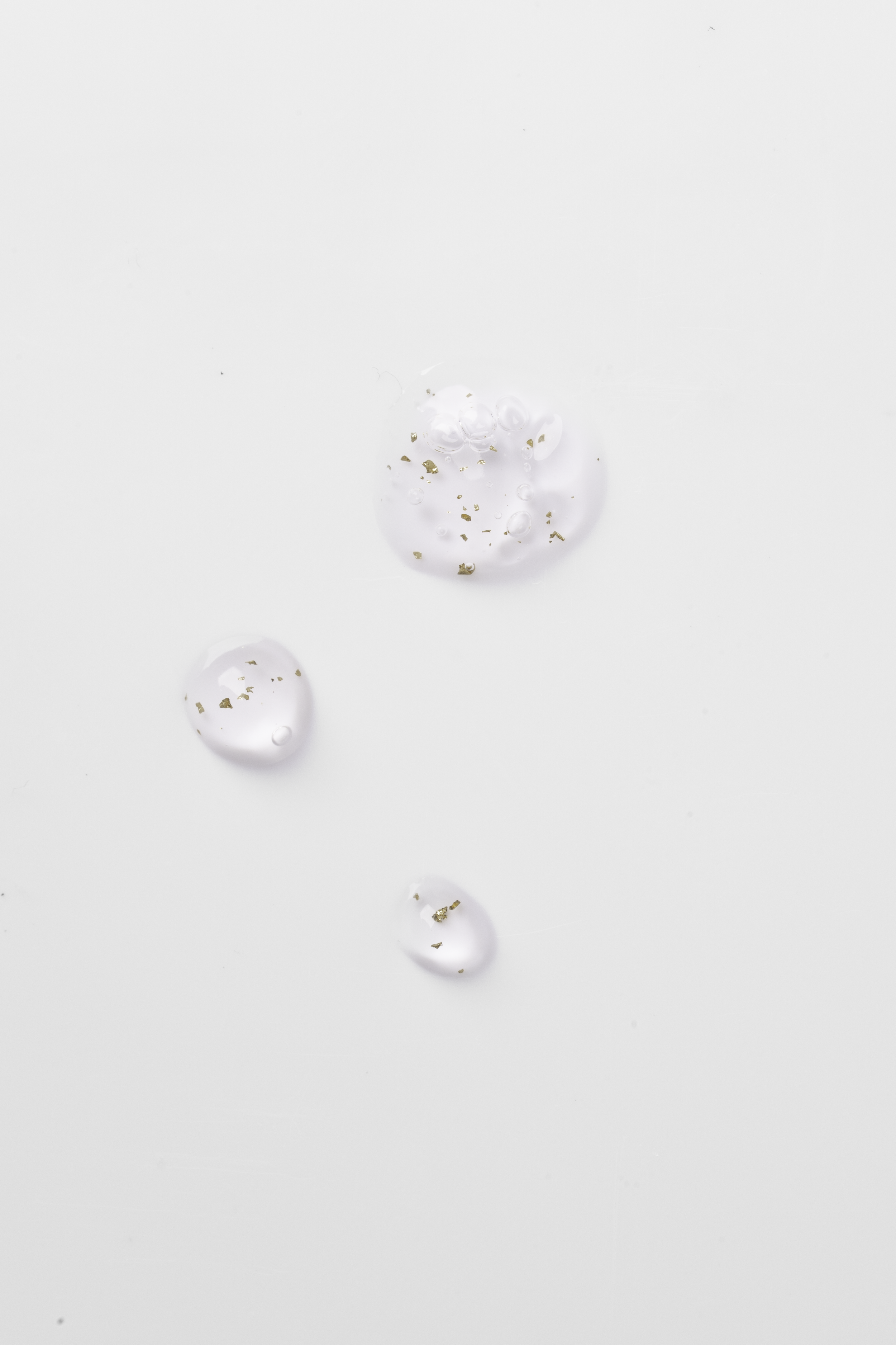 Hvide dråber med guldstøvkorn på en hvid baggrund.