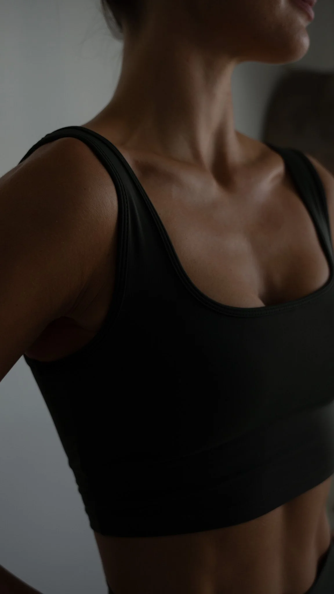 Tæt på en kvindes skulder og bryst, iført en sort top.