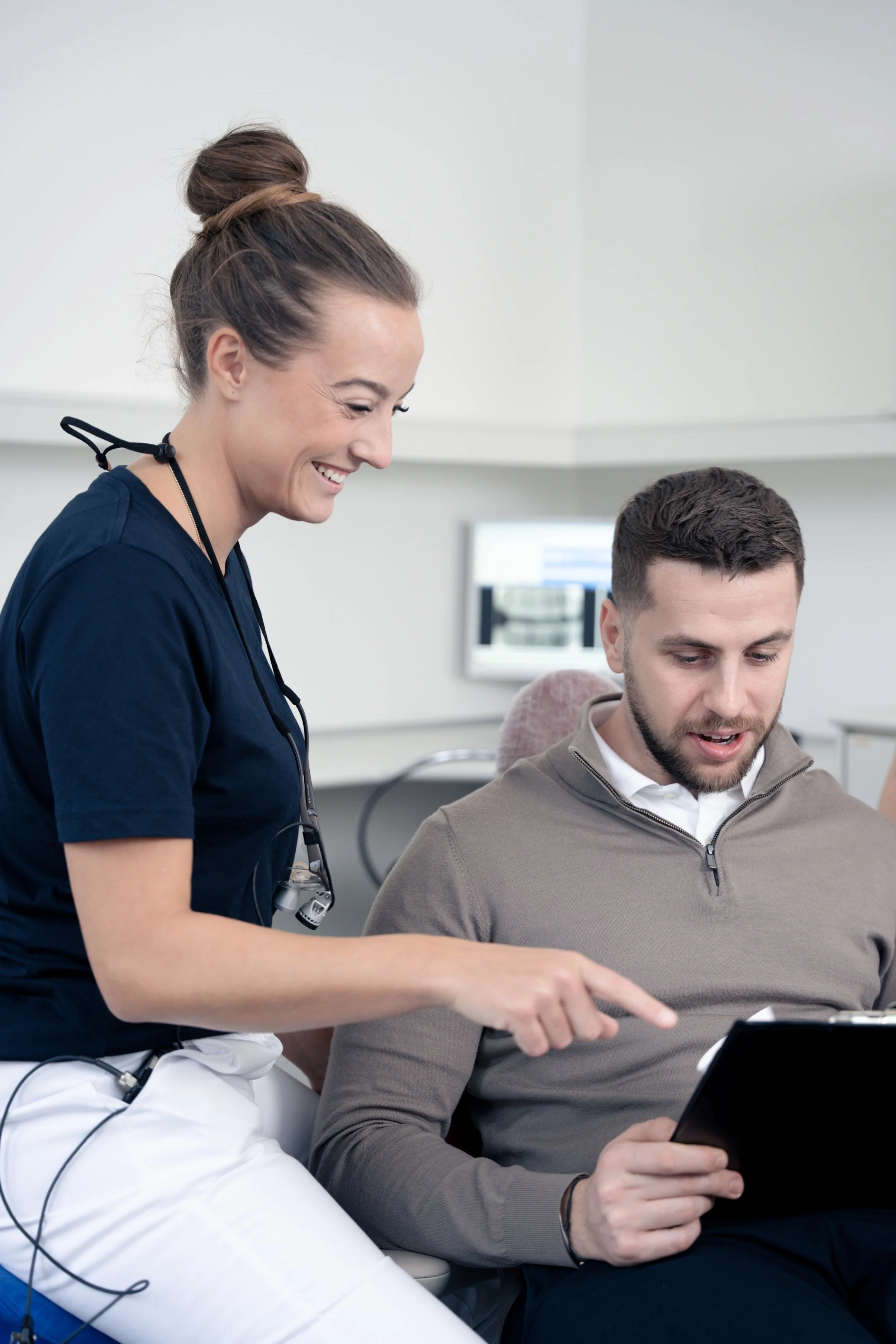 En sundhedsarbejder og en mand, der bruger en tablet i et klinisk miljø.