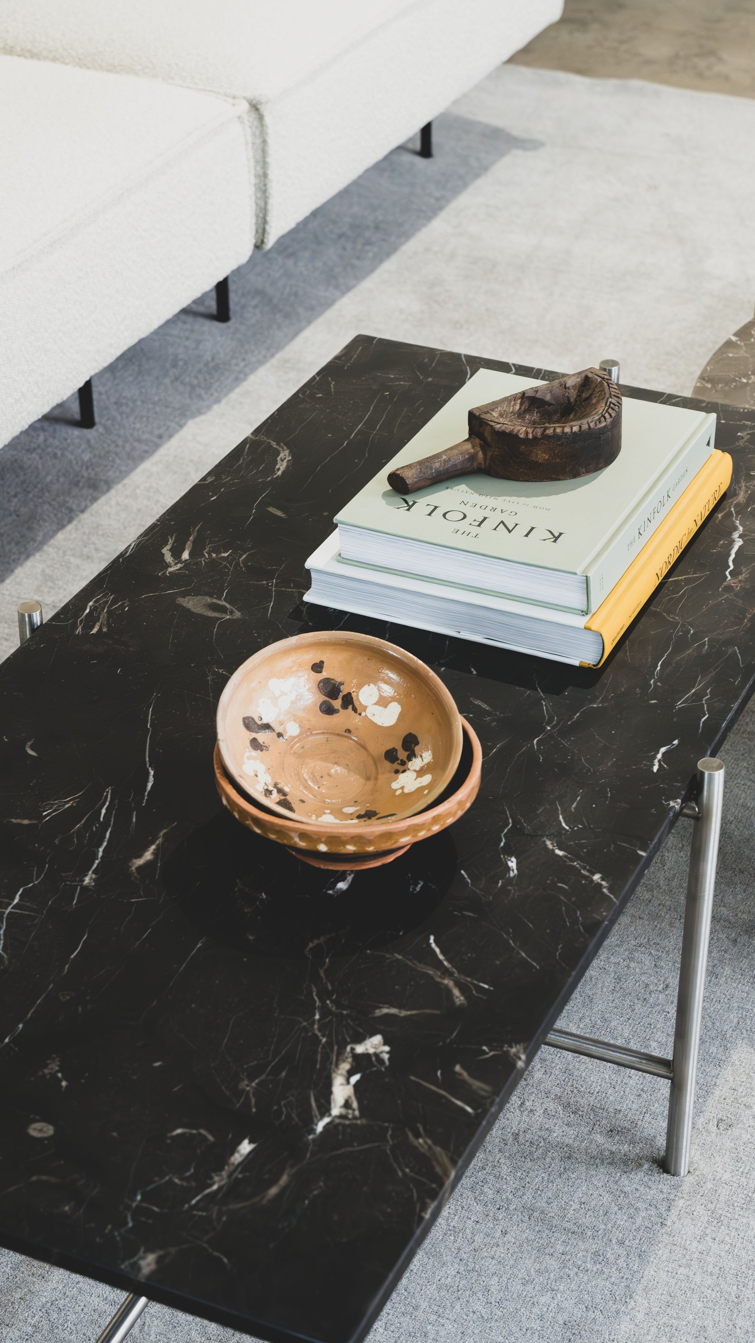 Sort bord med to keramikskåle og en bunke bøger med en træskrænk på toppen.