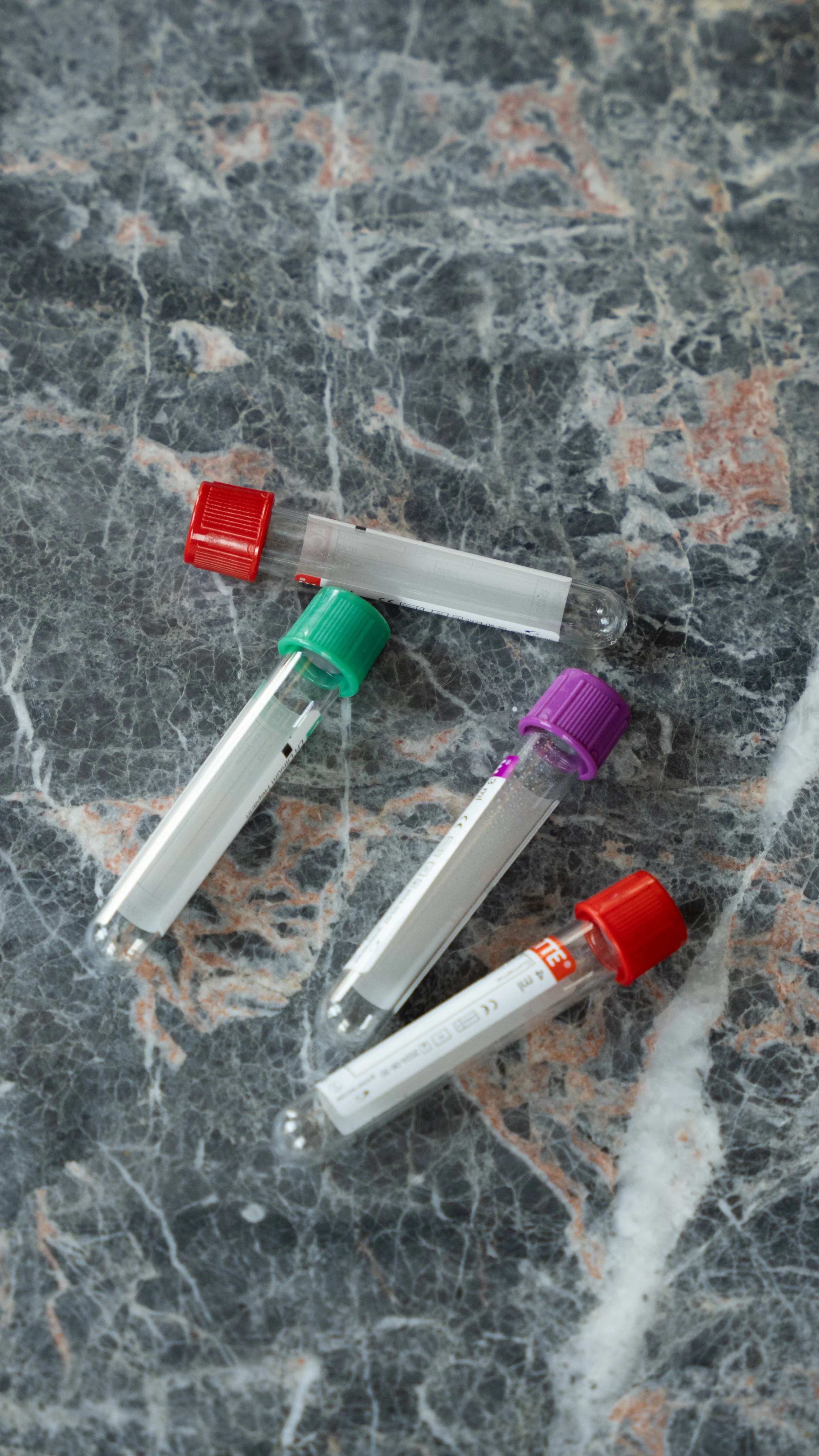 Fire laboratorierør med forskellige farvede låse på en marmoroverflade.