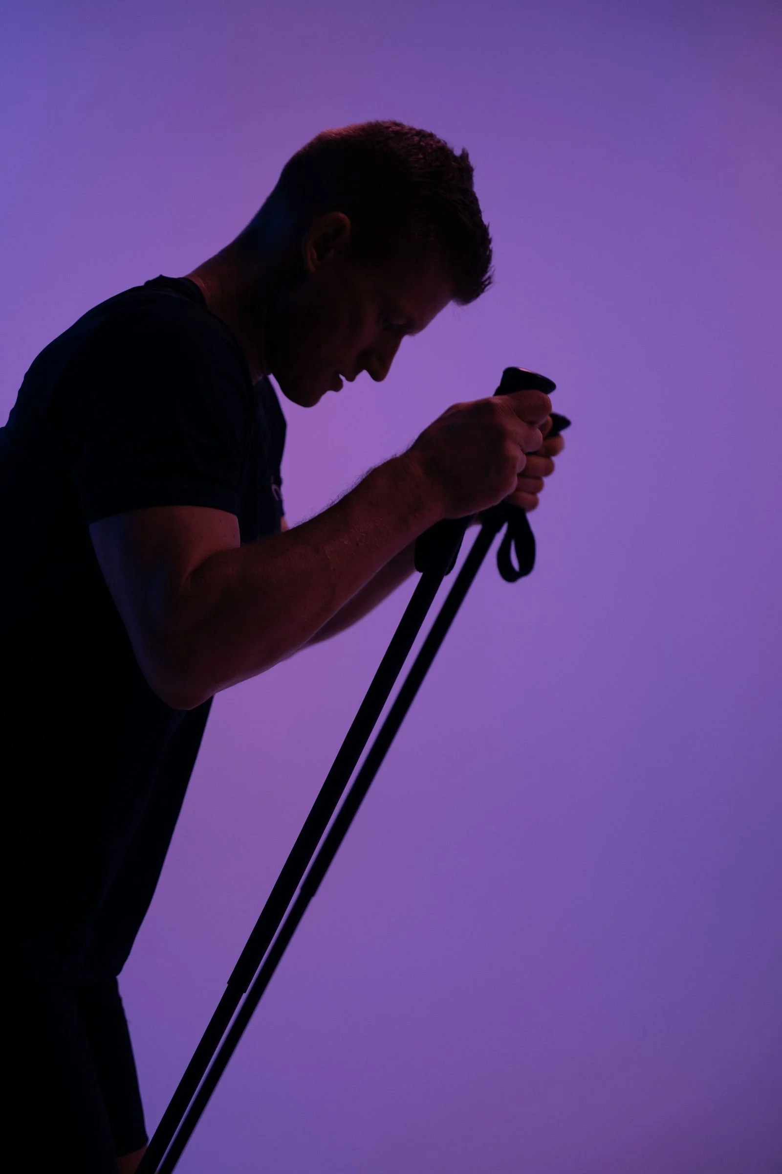 Silhuet af en mand med strejf af blå og lilla baggrund, han holder to stropper til træning.