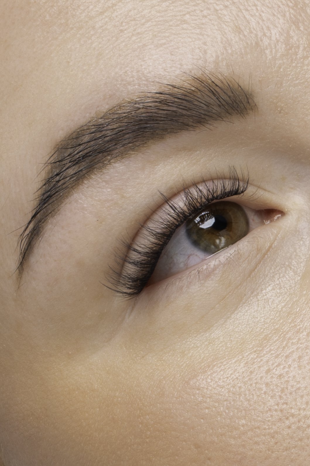 Nærbillede af et menneskes øje med lange, adskilte øjenvipper og velplejet bryn.