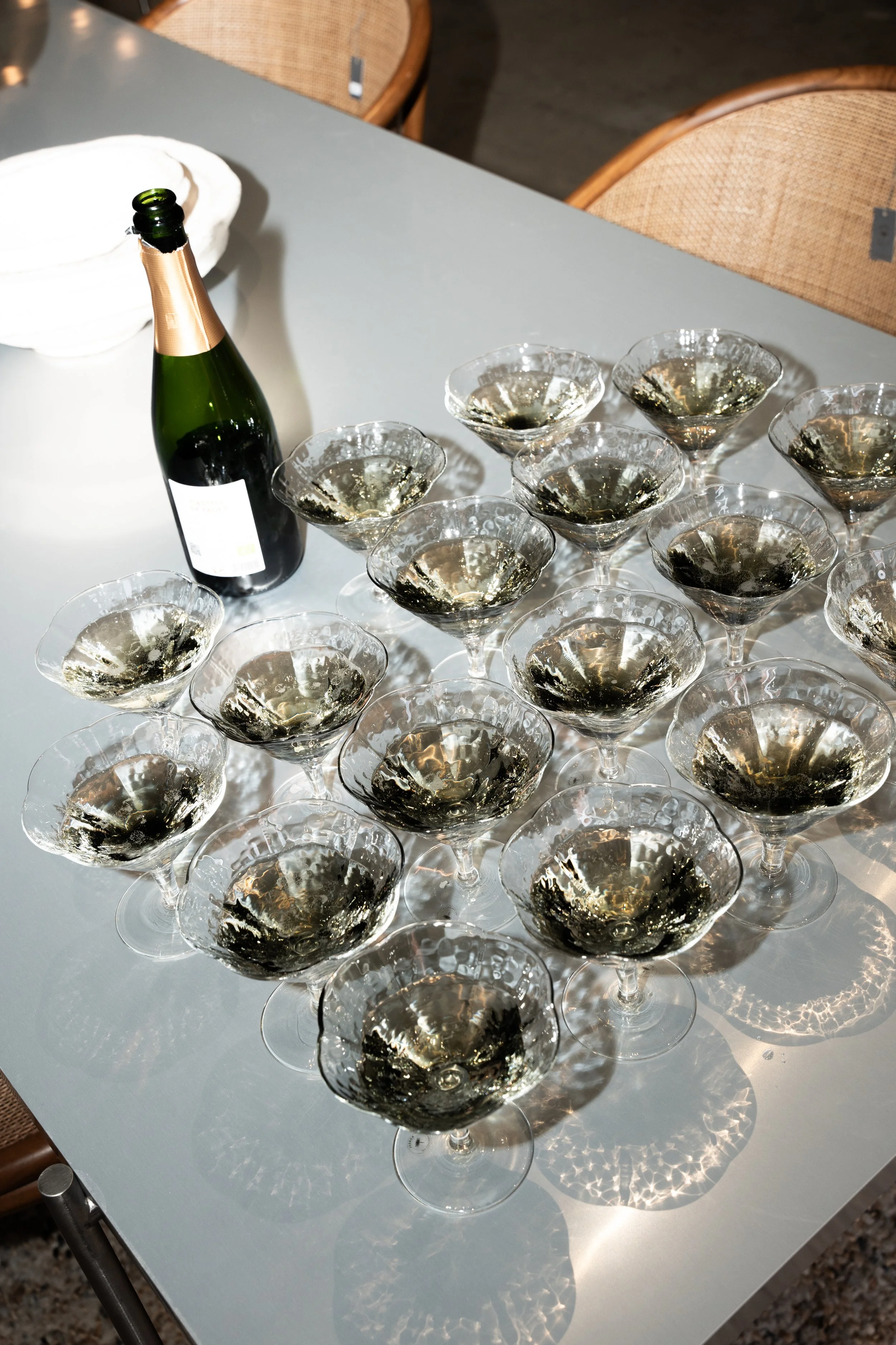 Billede af en bord med flere tomme champagneglas, en flaske champagne og en hvid skål.