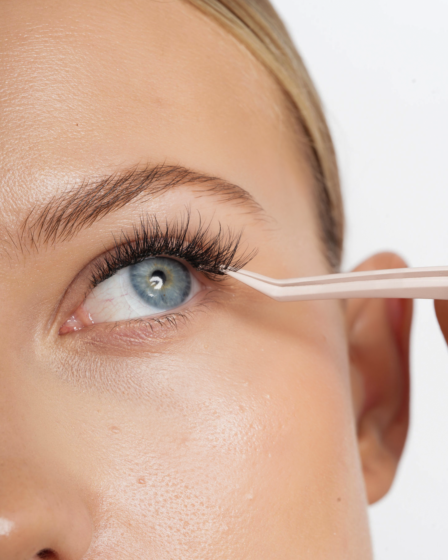 En person får påført øjenvipper med en påsætter.